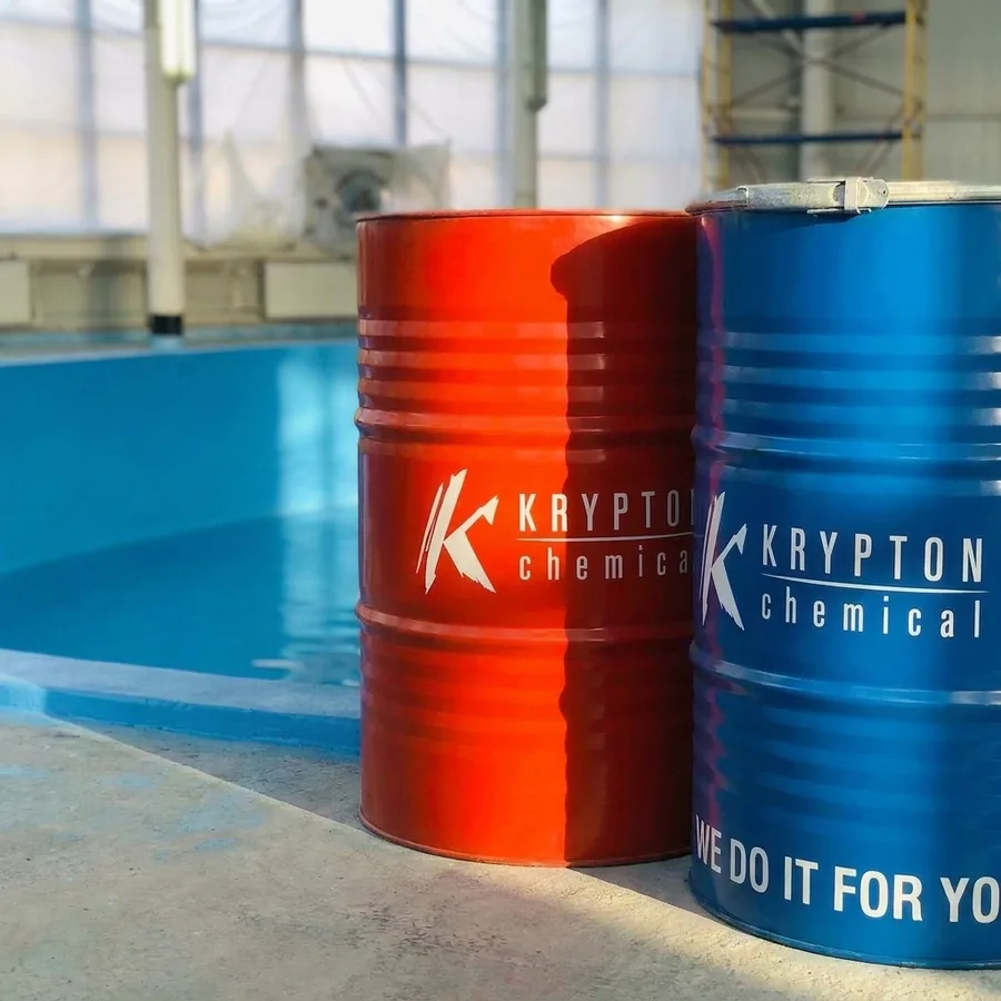 Red and blue Krypton Chemical 2K drums standing together on a warehouse floor beside a blue-coated basin