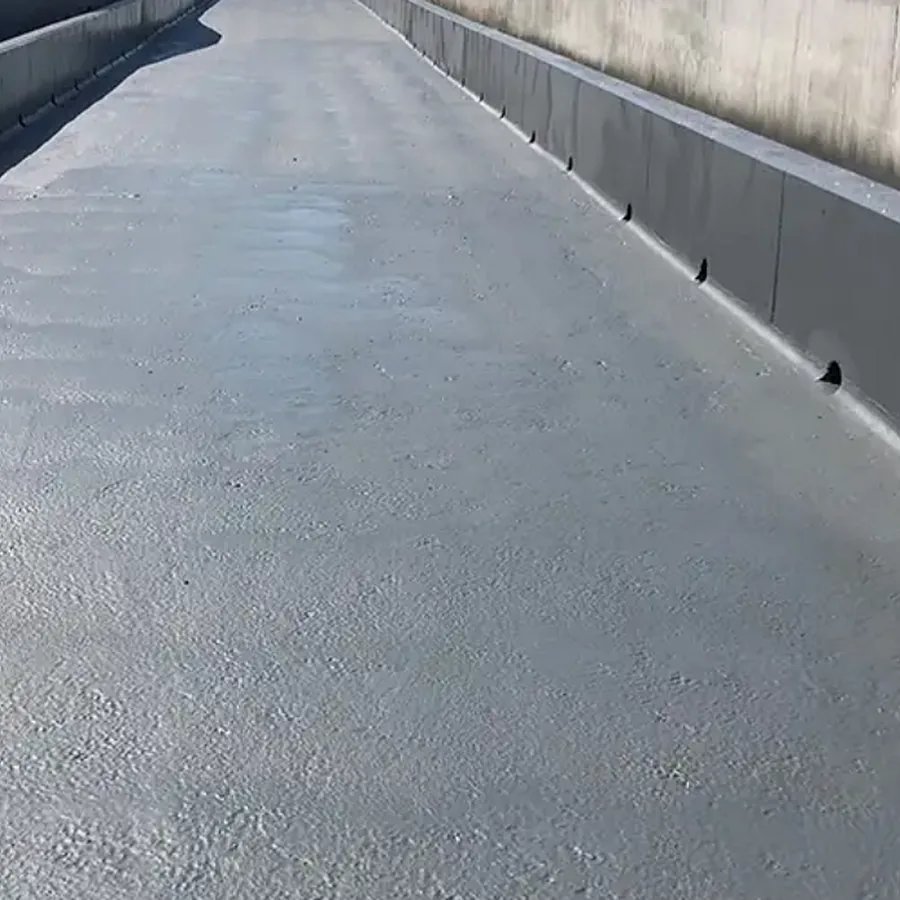Grey slip-resistant polyurea coating on a long concrete deck with coved parapets and drainage scuppers