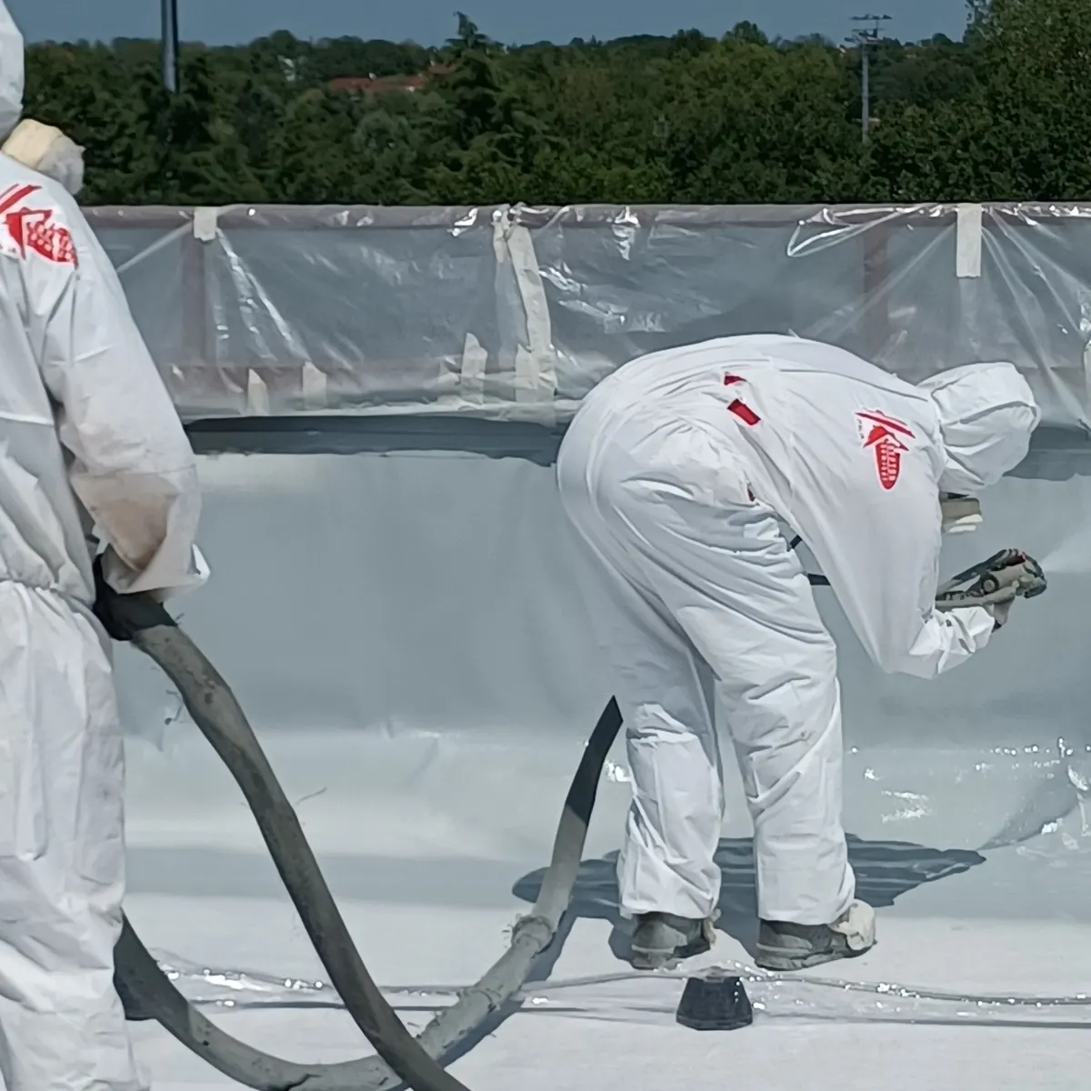 Close-up of spray gun applying membrane at parapet, Milan