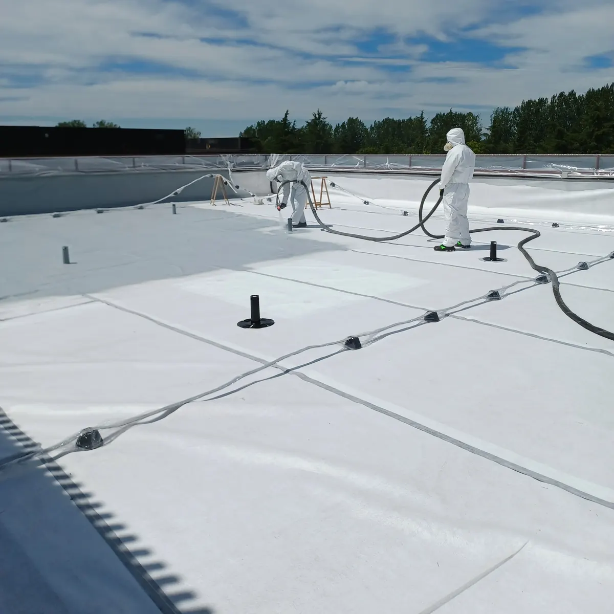 Two applicators hot-spraying white membrane, Milan bank