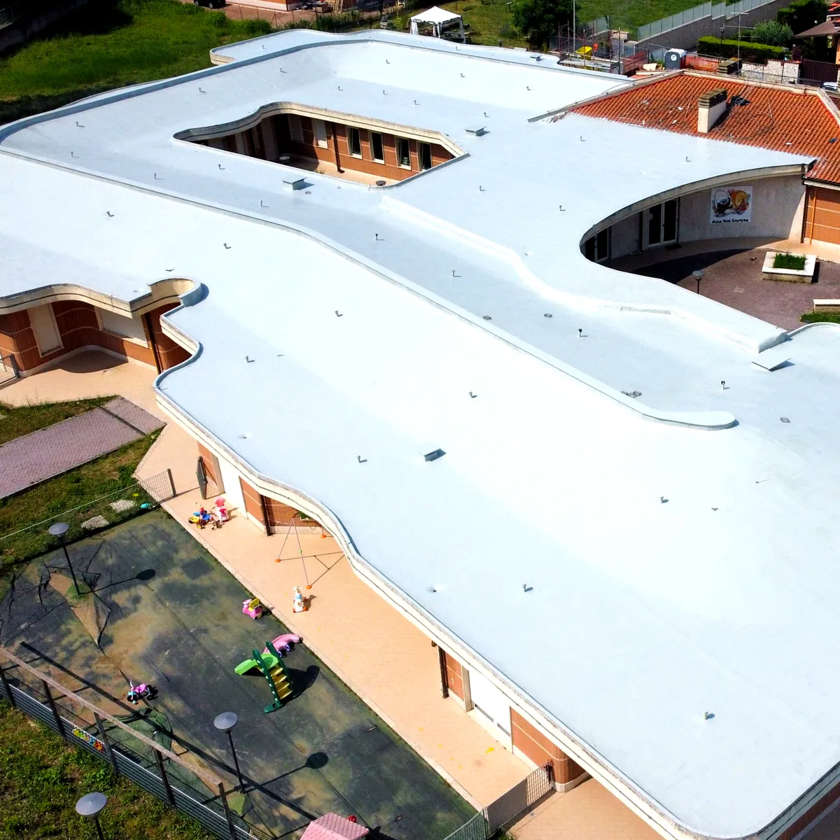 Bitumen roof renovation Rome: curved white roof over the nursery playground