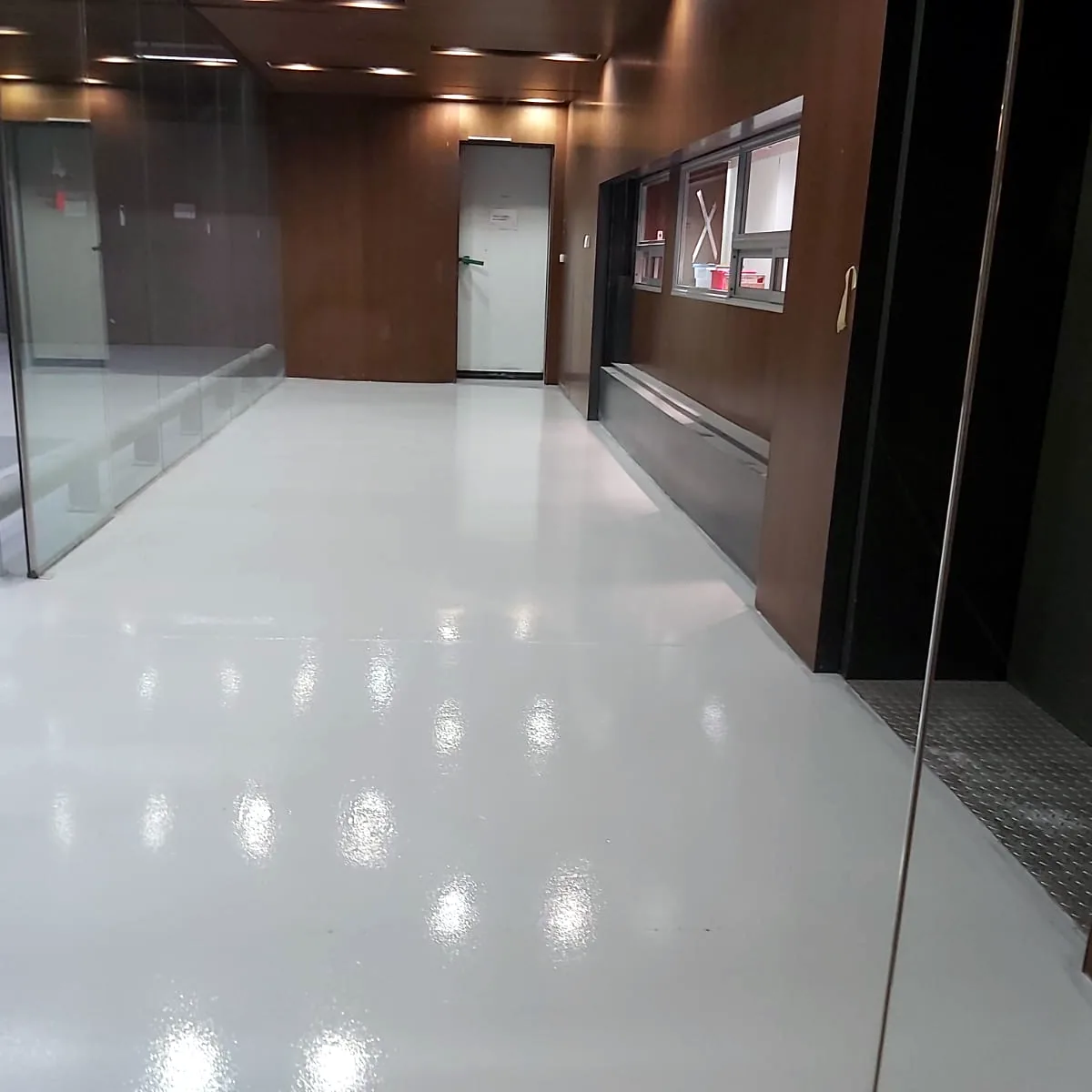 Bright corridor with a glass balustrade and wood panels