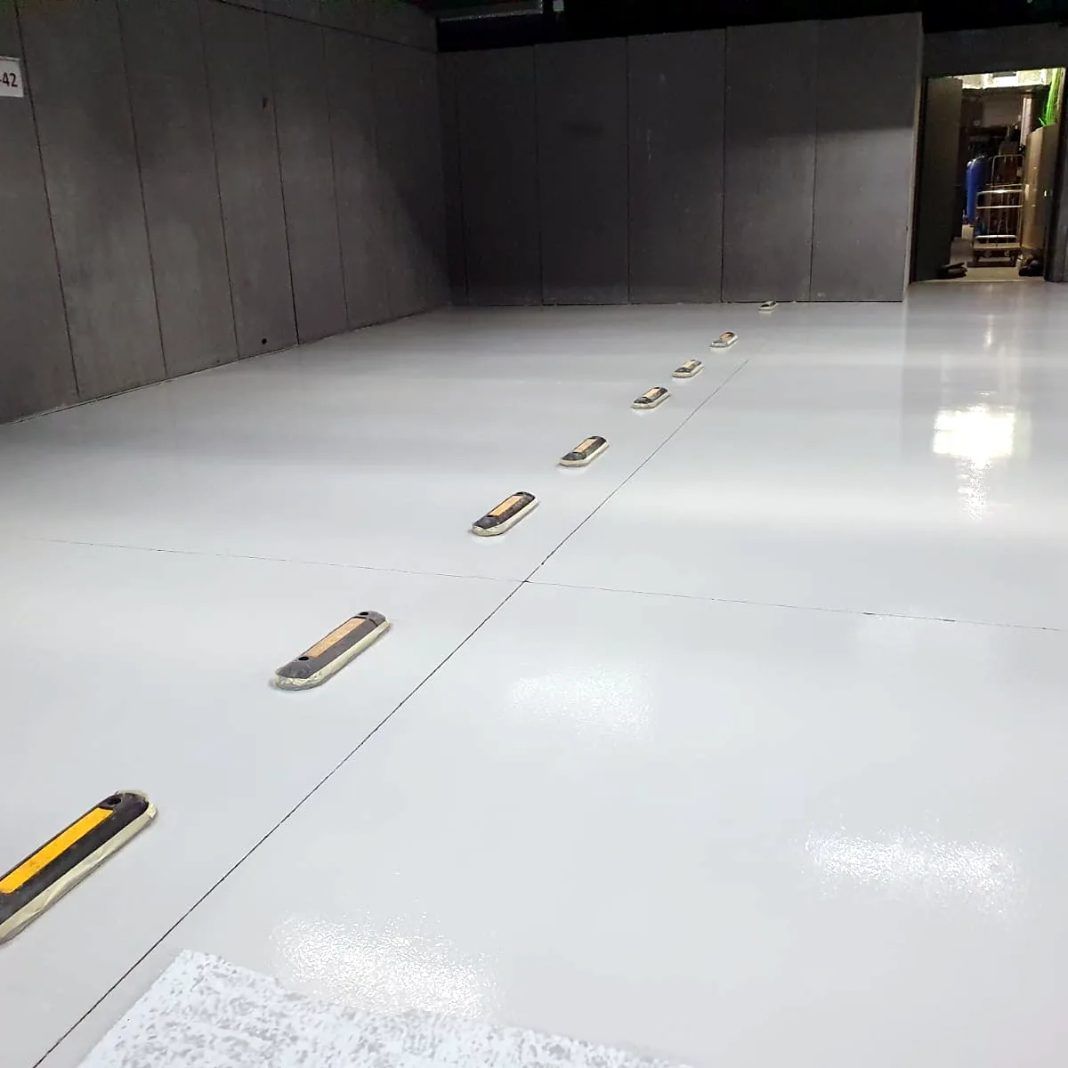 Light floor with yellow and black floor markers along the wall