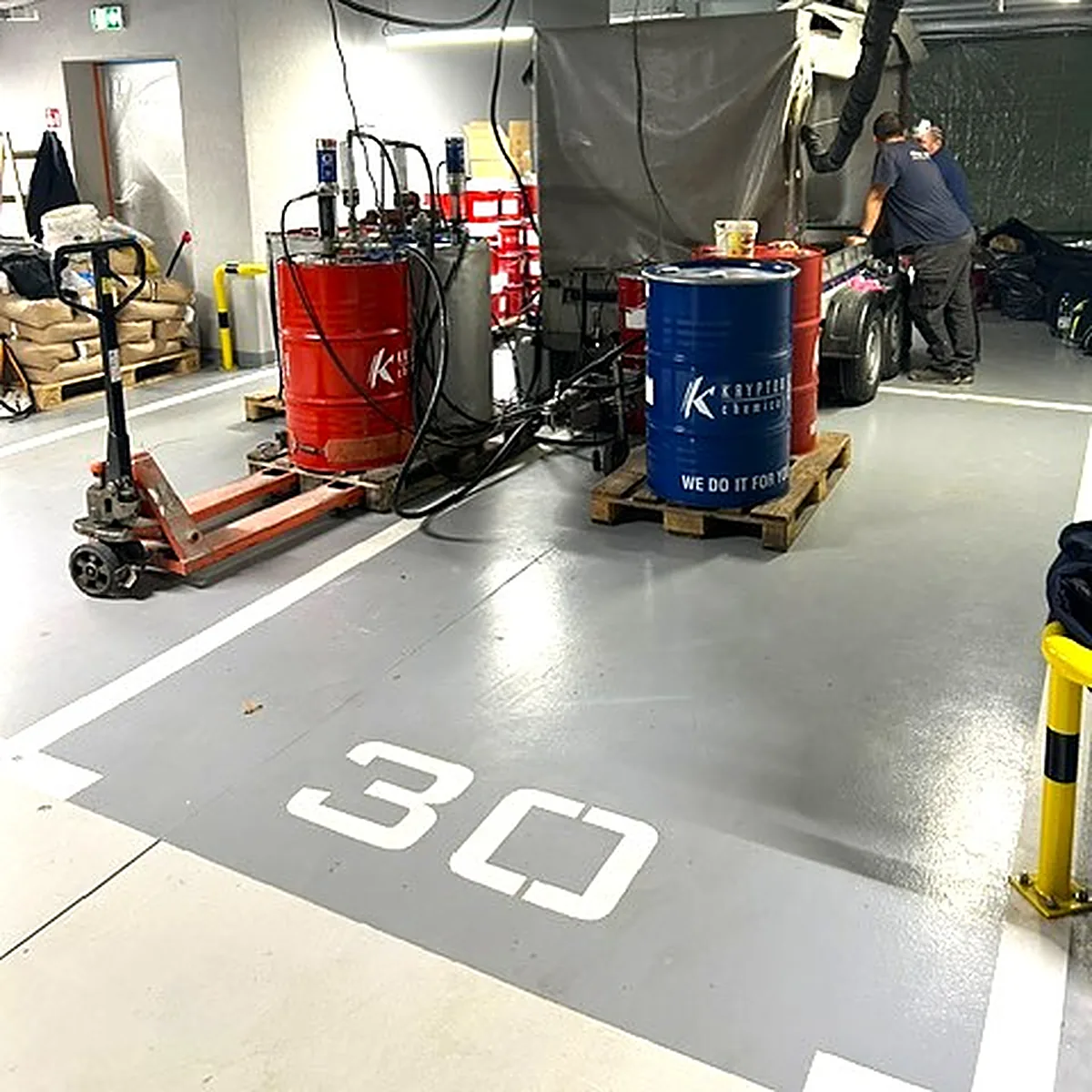 Spray rig with red and blue drums on a grey parking bay marked 30, Kraków