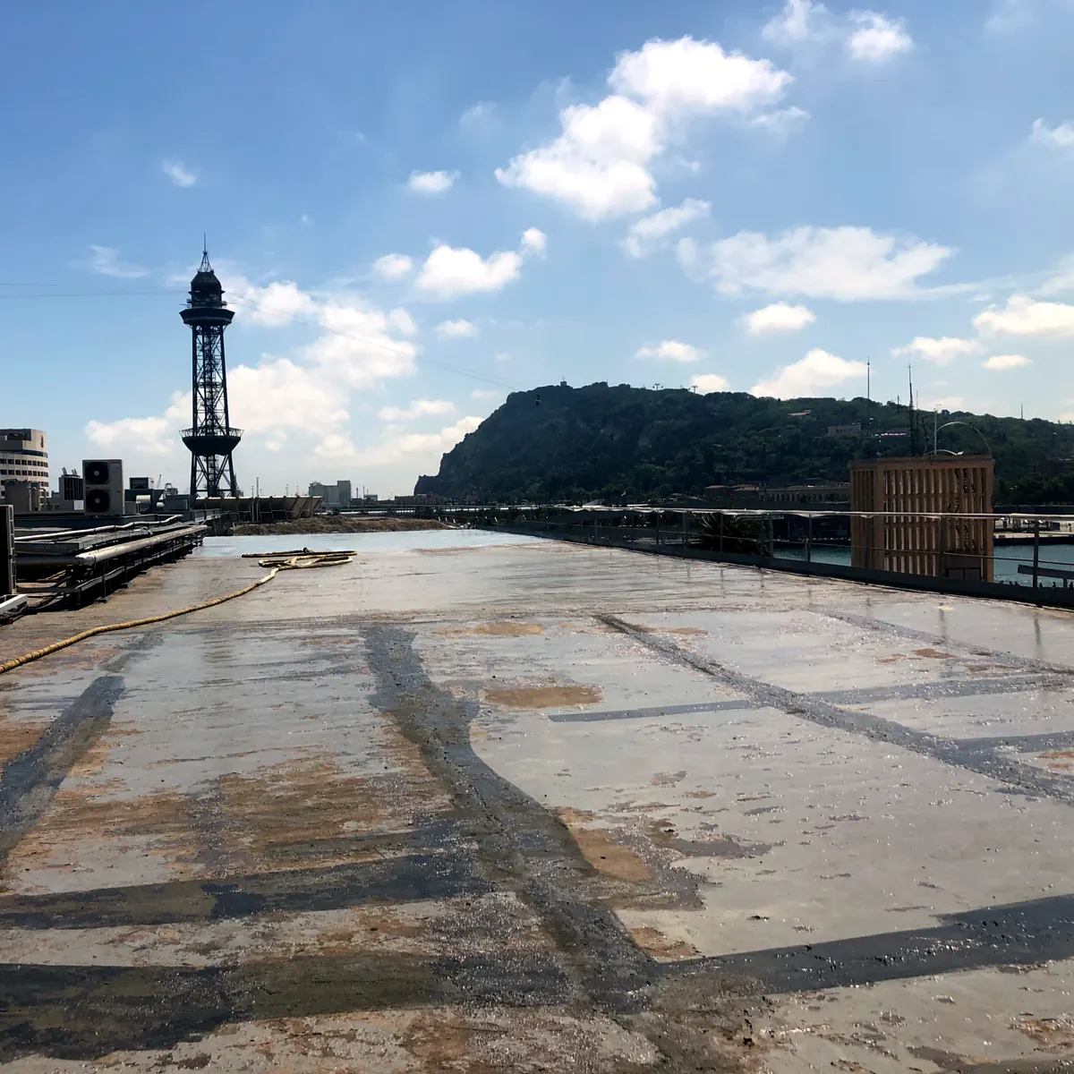 Juntas de losa abiertas, bajo la torre del teleférico de Port Vell. Cubierta vieja con las líneas de junta y la torre del teleférico. Barcelona.
