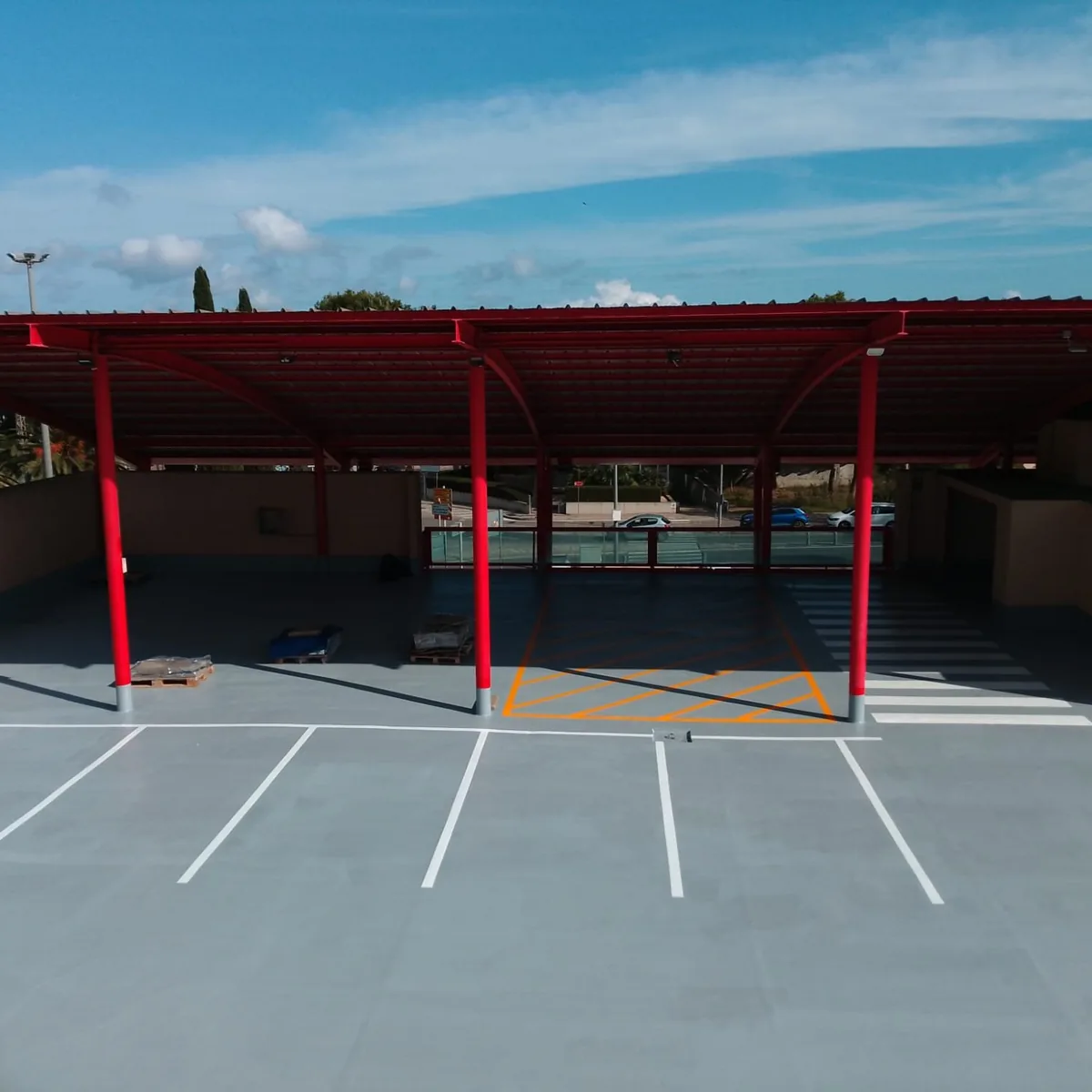 Finished blue car park roof with red canopies and white bay lines, Mallorca