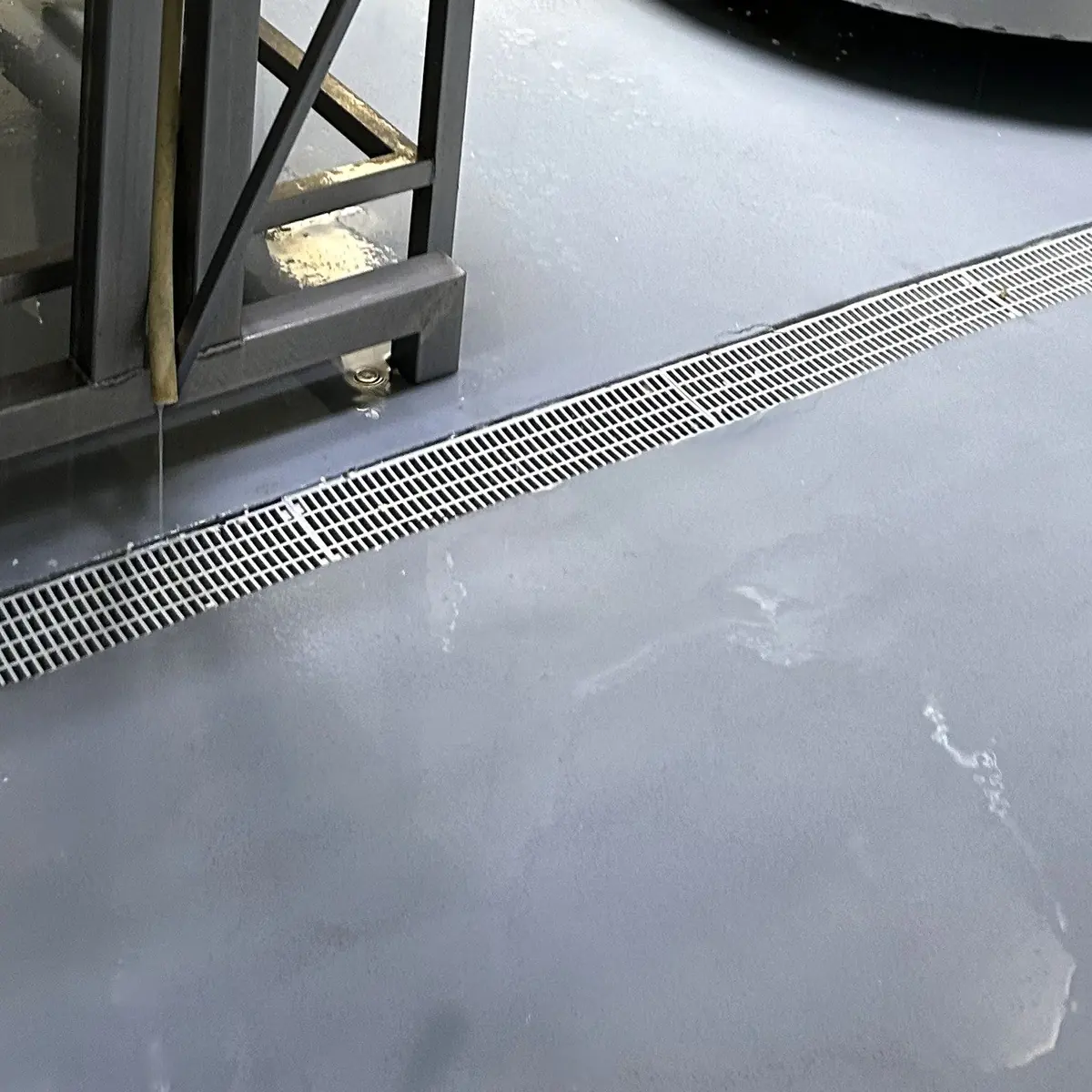 Grey floor beside a stainless drain channel in the dairy, Ciutadella