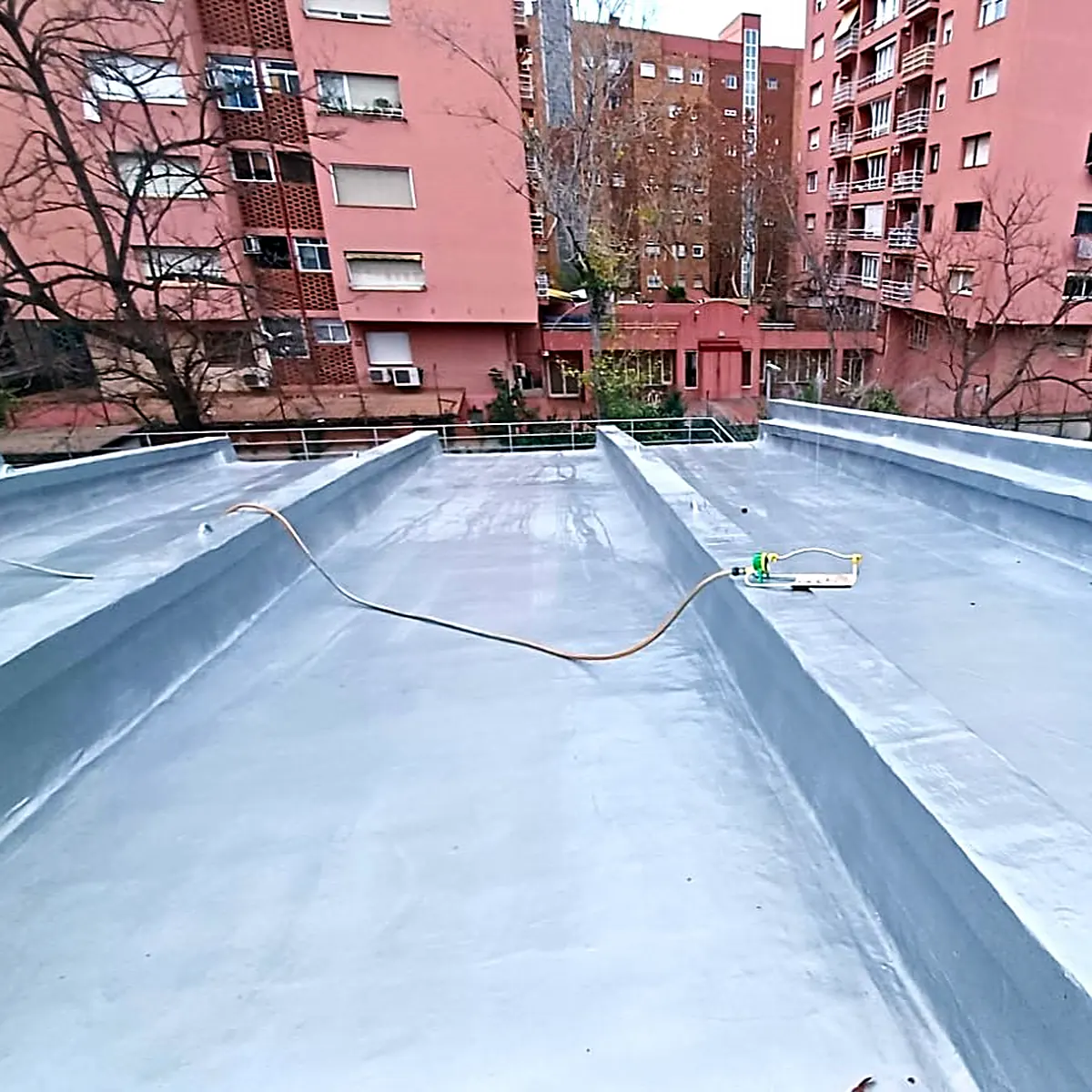 Coated roof valley between two upstands, with a hose across it