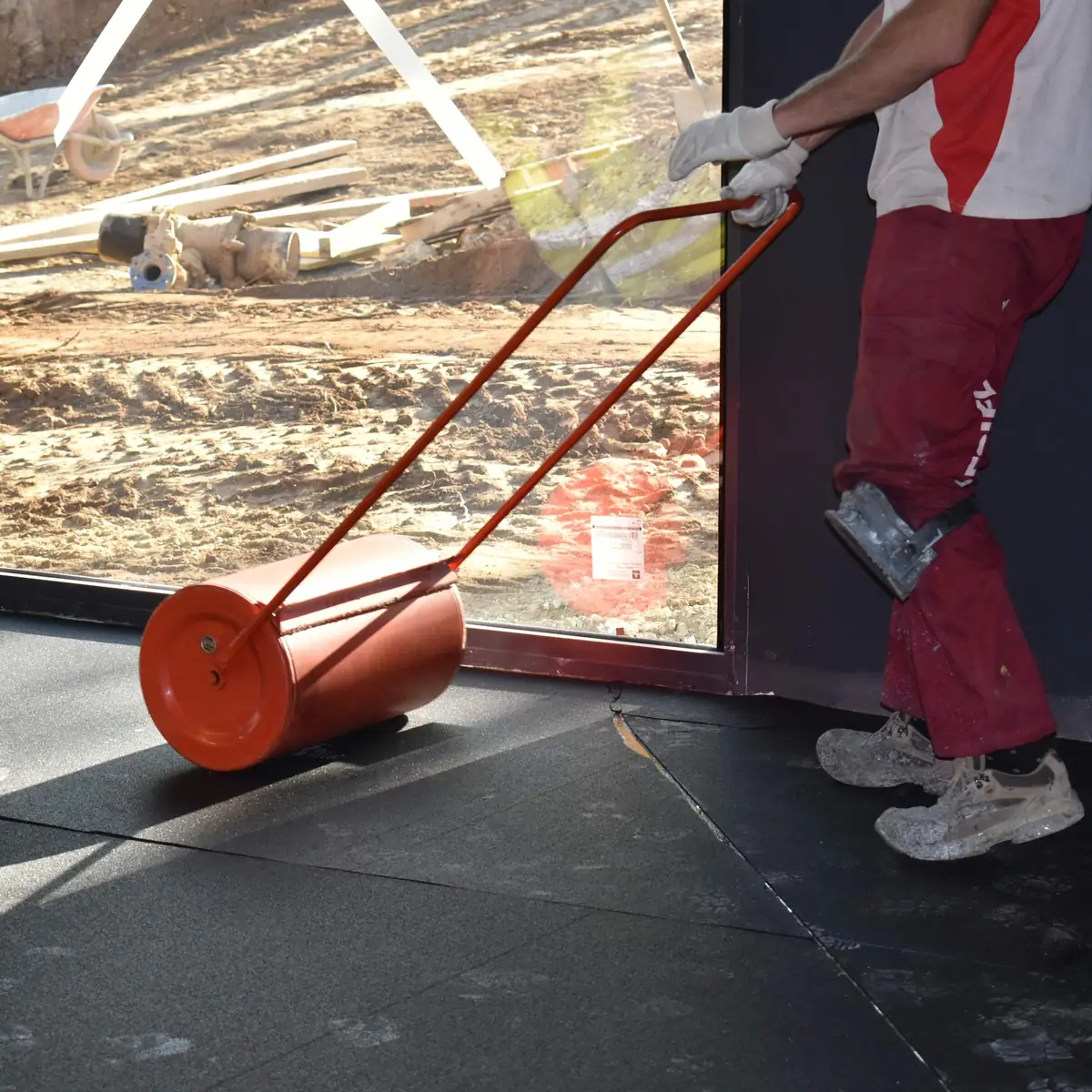 Worker rolling the rubber mat into the adhesive, Salou