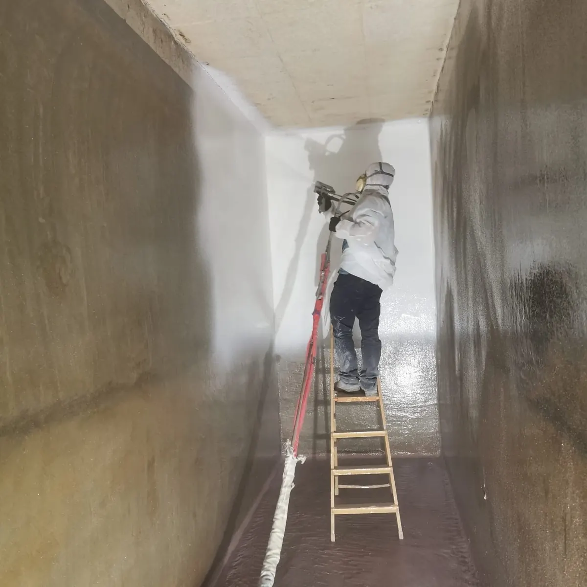 Applicator rolling white lining high on tank wall, Tortosa
