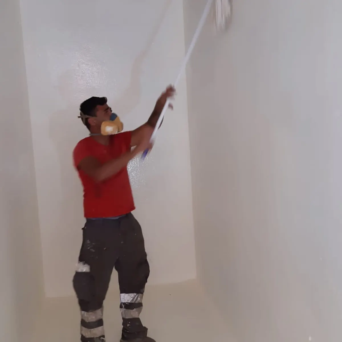 Worker rolling white polyurea on tank wall, Tortosa