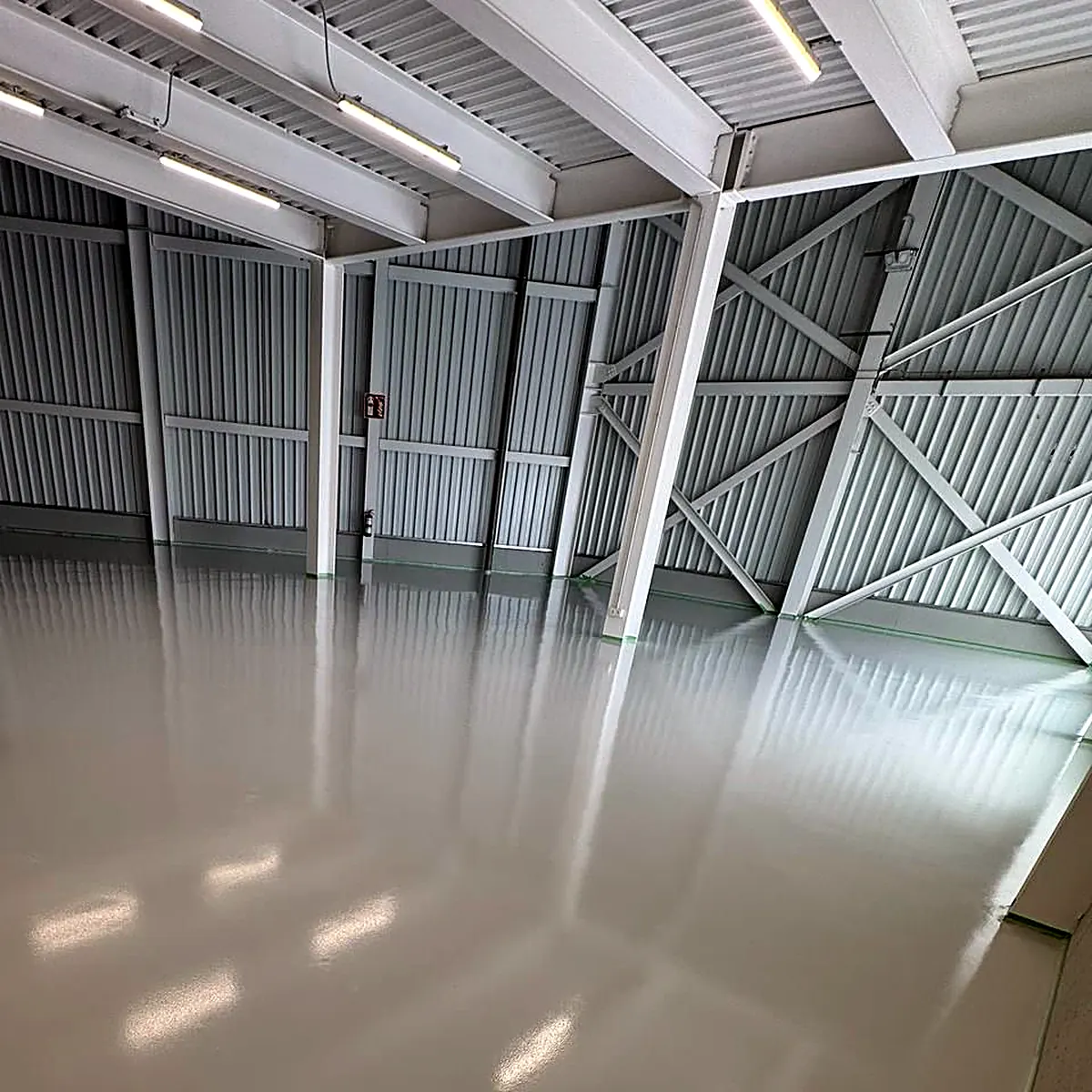 Glossy floor reflecting the roof lights in the braced steel hall
