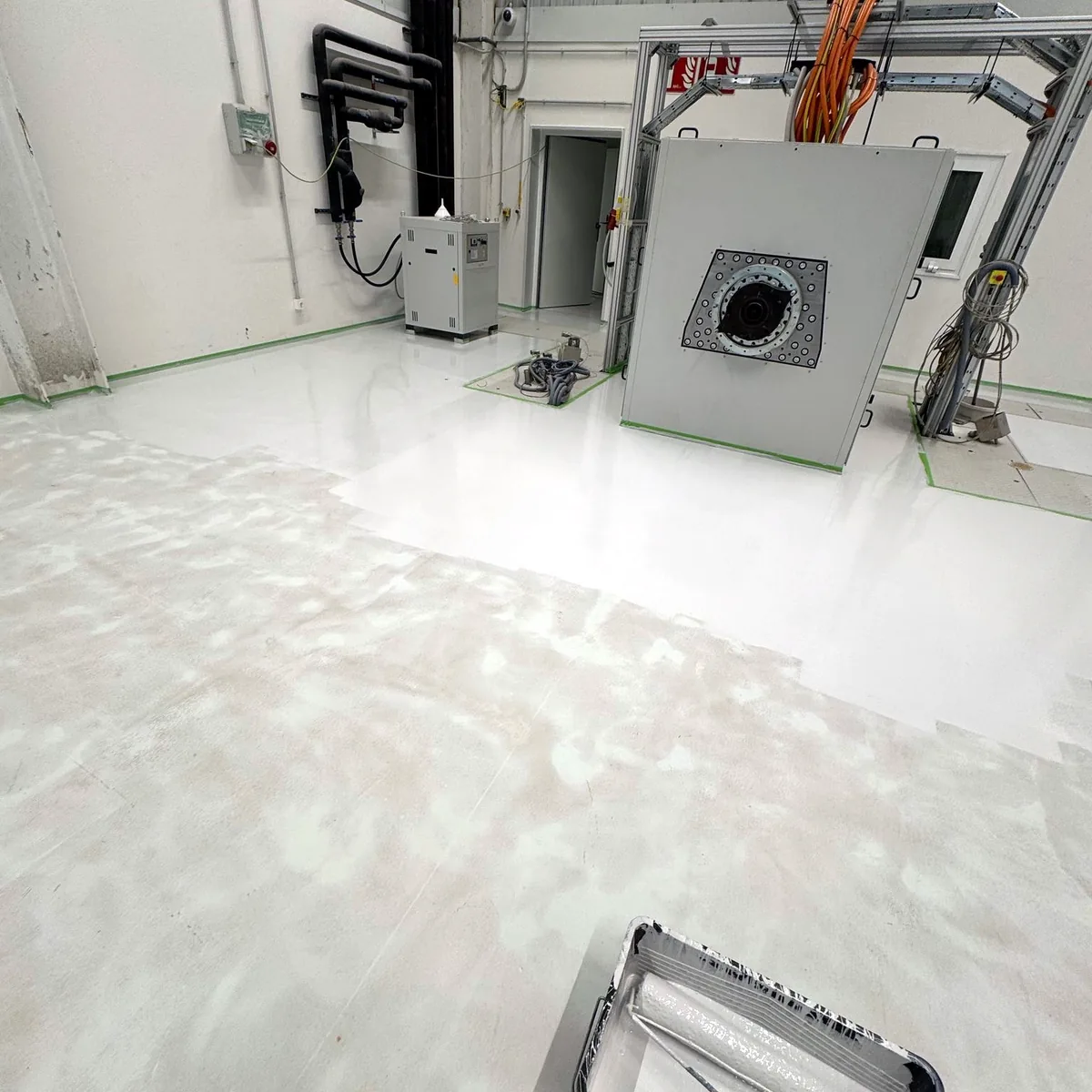 Plant room floor with equipment against the wall and a roller tray