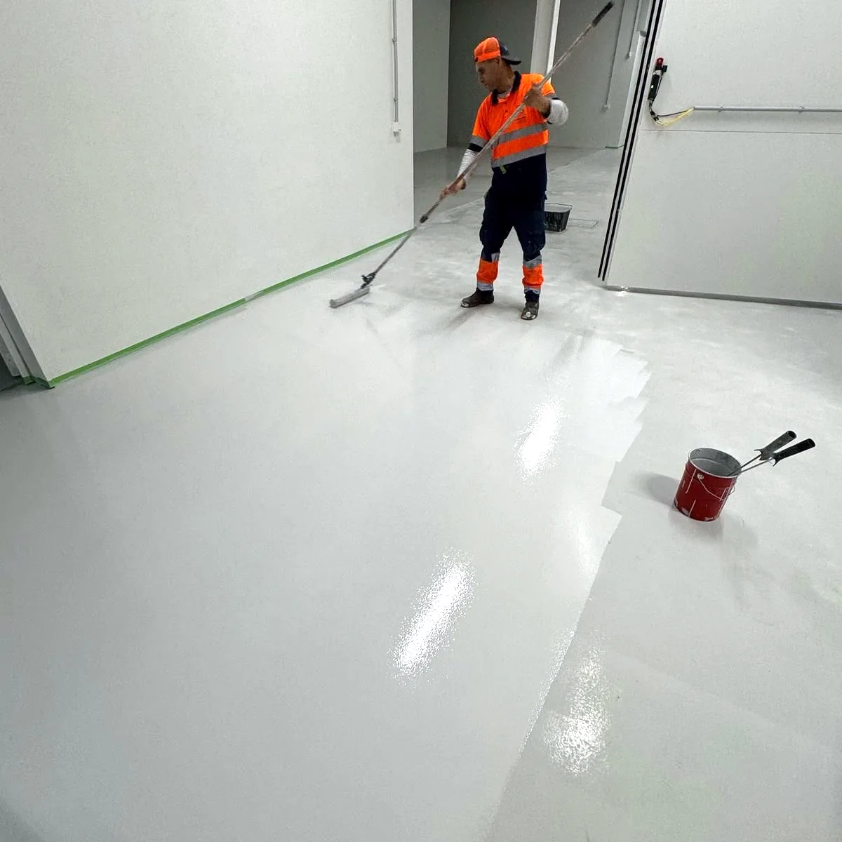 Worker in orange rolling a coat across the floor