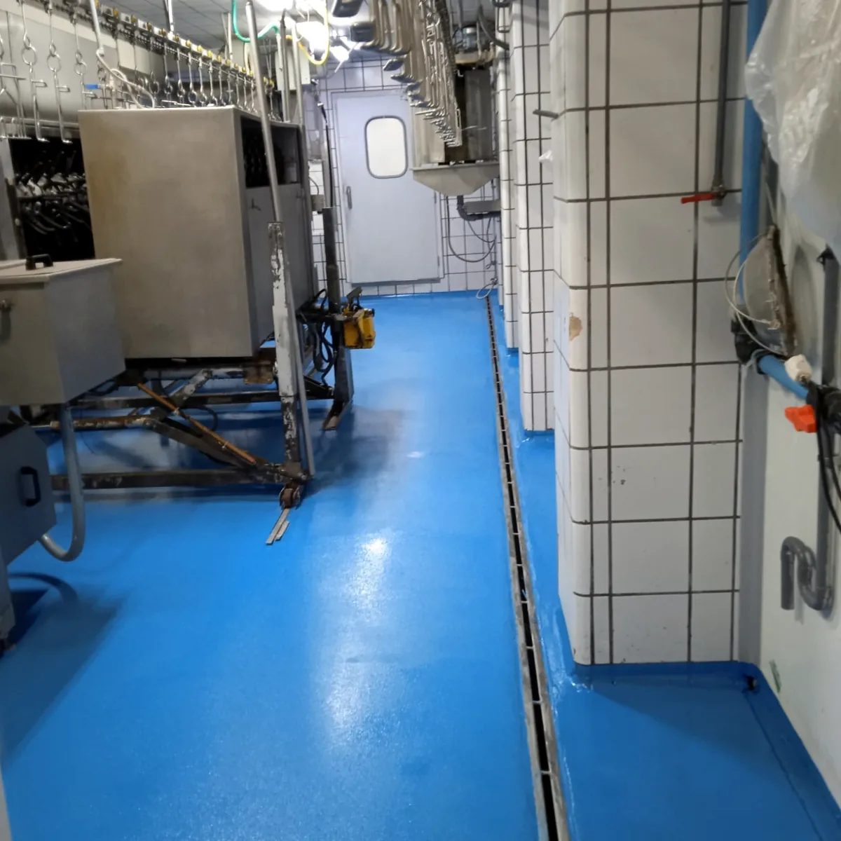 Blue floor beside a floor drain and steel machines, Prats de Lluçanès Blue floor beside a floor drain and steel machines, Prats de Lluçanès