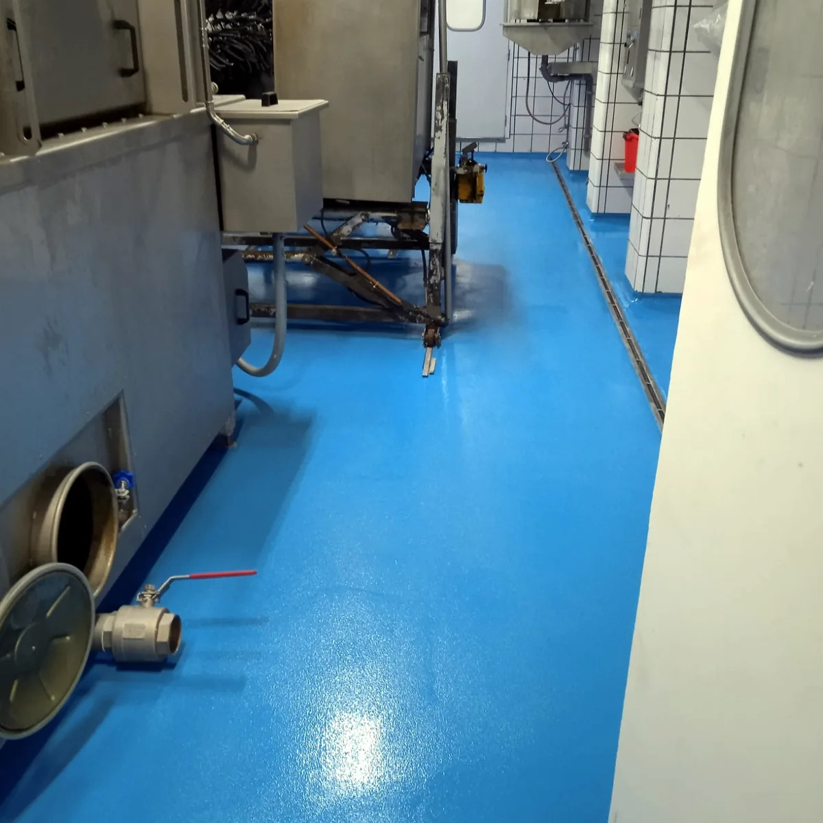 Blue floor running between production machines and a tiled column Blue floor running between production machines and a tiled column