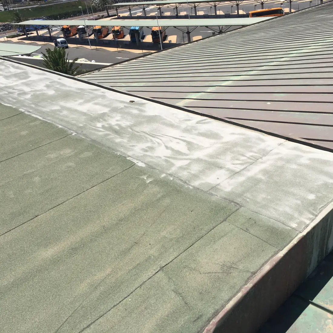 Green membrane edge beside the metal roof, with the bus stands below