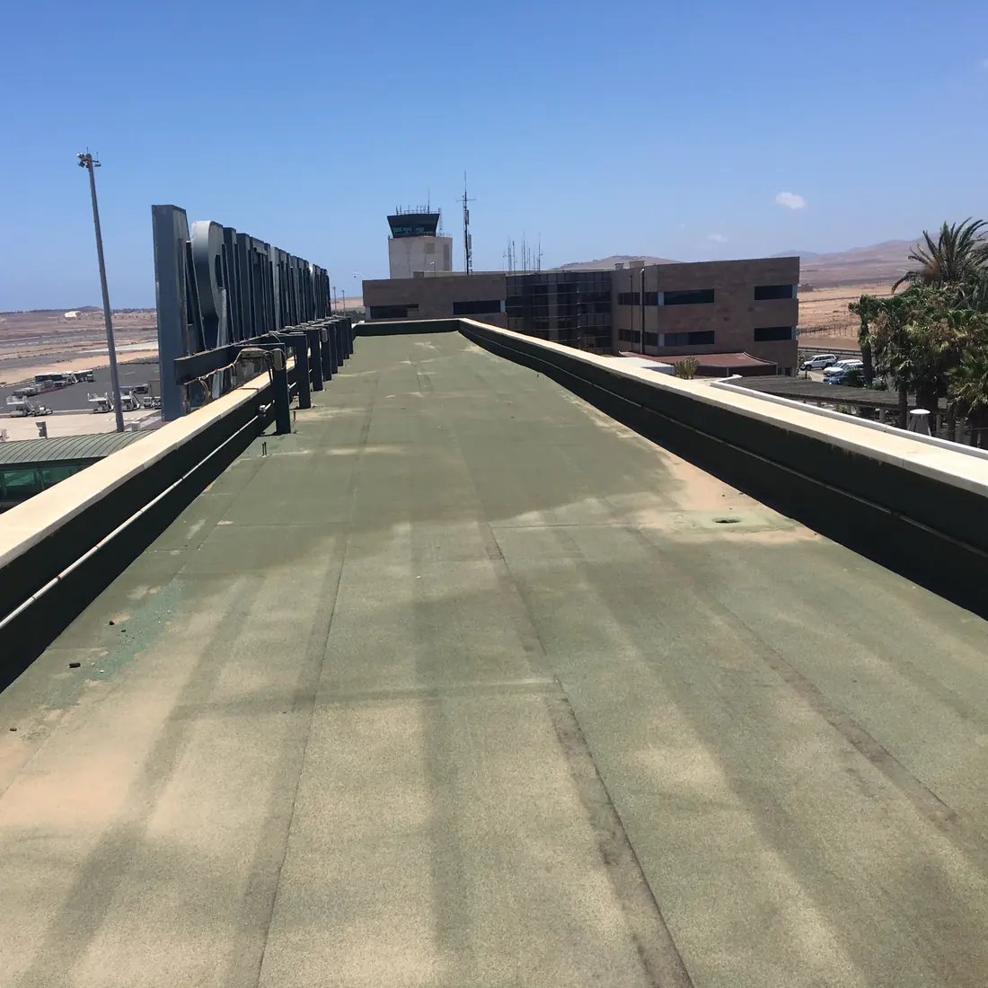 Narrow green roof between parapets, with the control tower behind