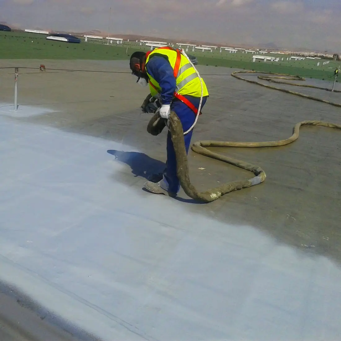 Close view of the spray gun laying the coat up to the roof edge