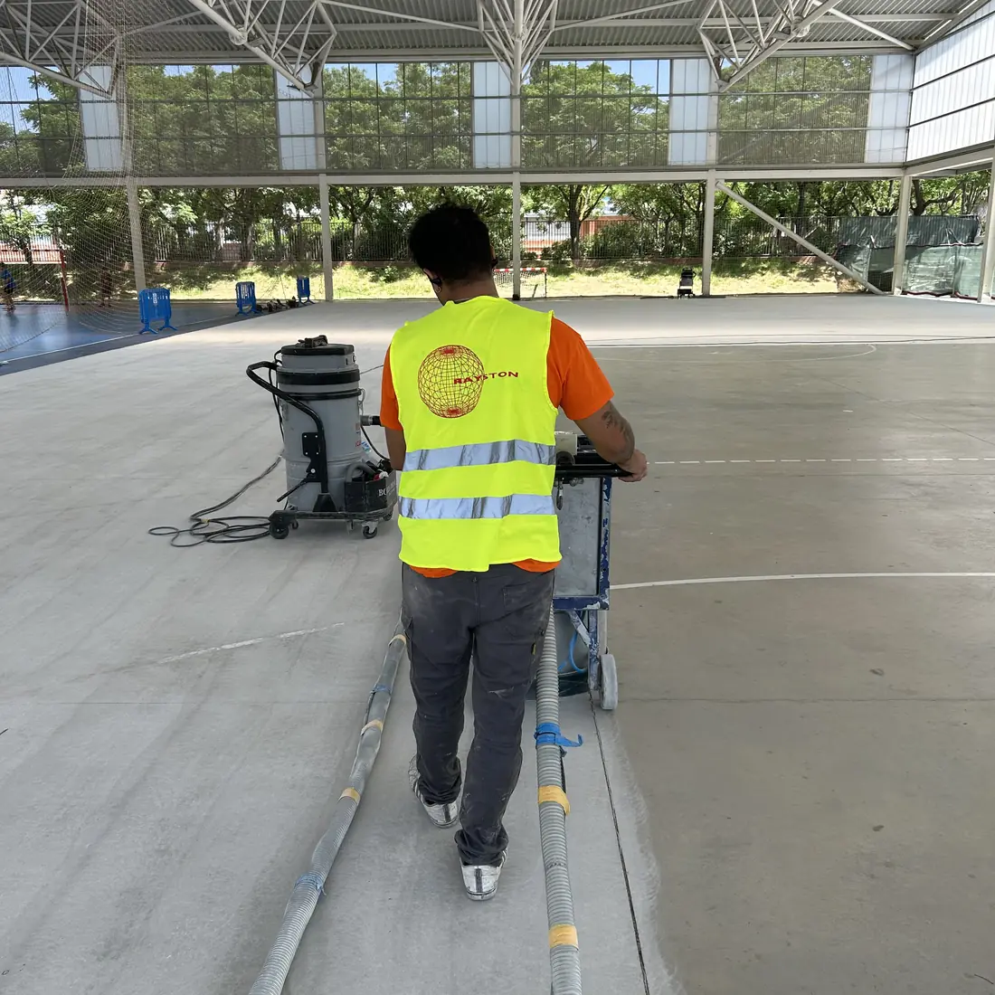 Worker grinding the grey slab in the sports hall Worker grinding the grey slab in the sports hall