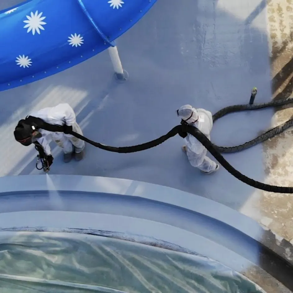 Two workers spraying the deck beside a blue slide Two workers spraying the deck beside a blue slide