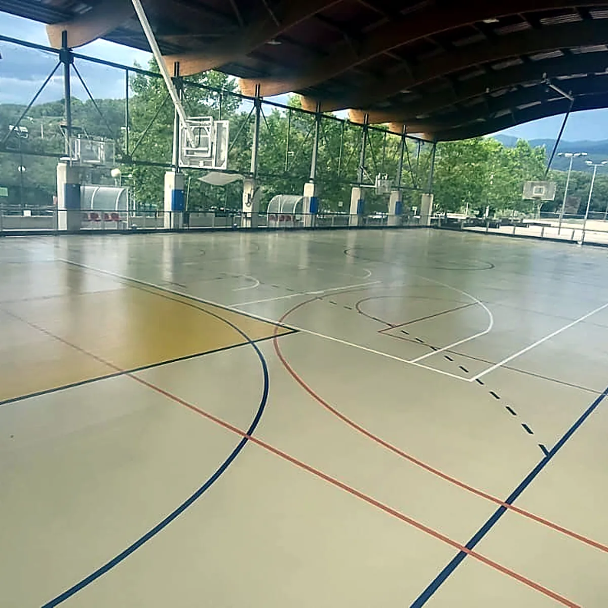 Pista cubierta con estructura de madera en el techo y colinas al fondo