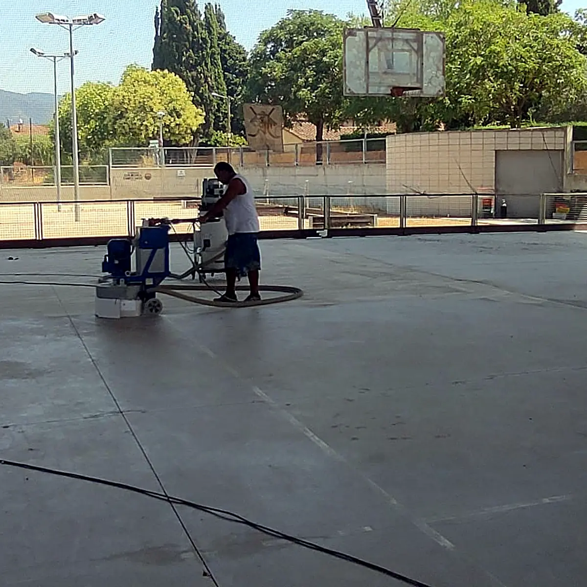 Operario desbastando la antigua superficie de la pista bajo la cubierta