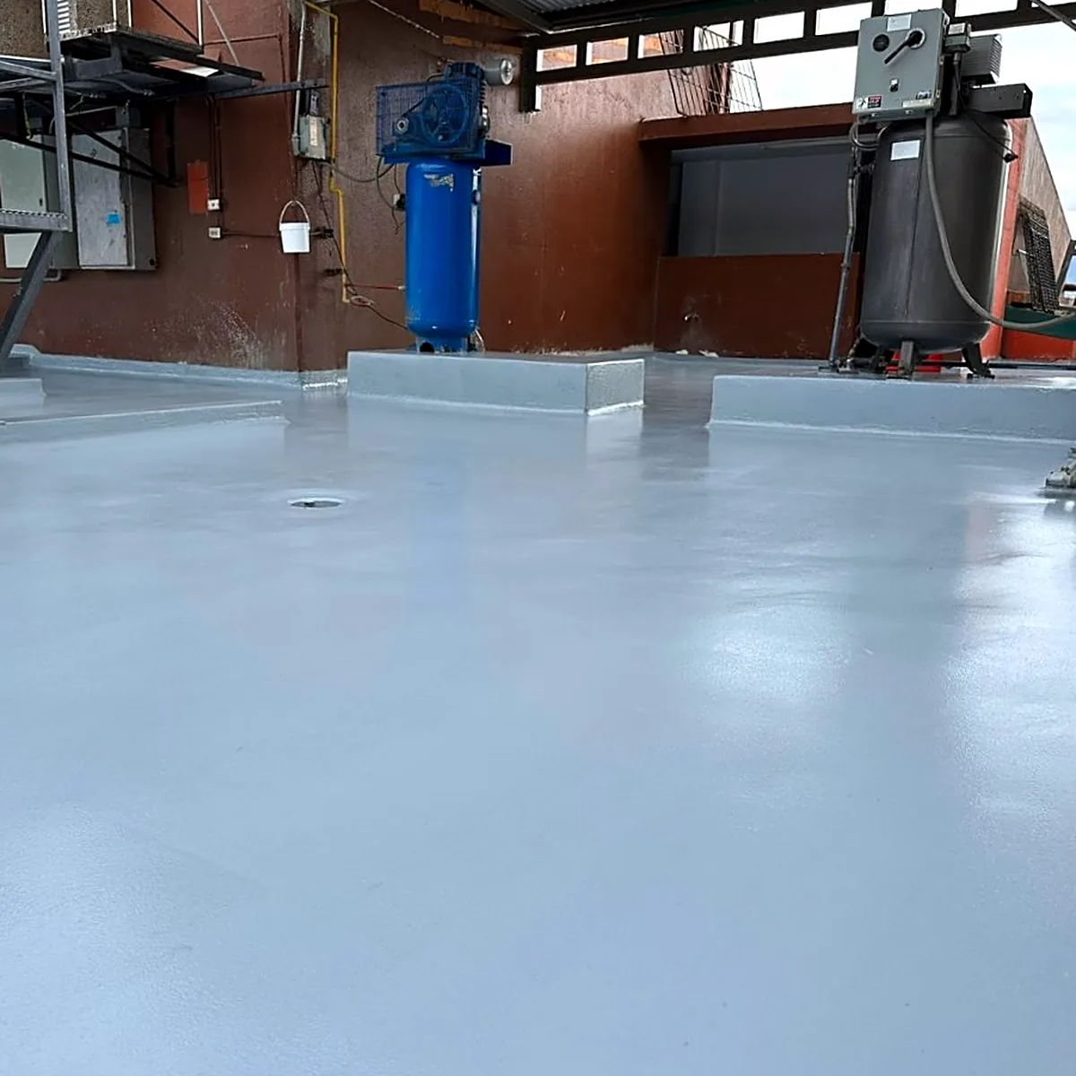 Finished grey roof area in front of blue equipment Finished grey roof area in front of blue equipment