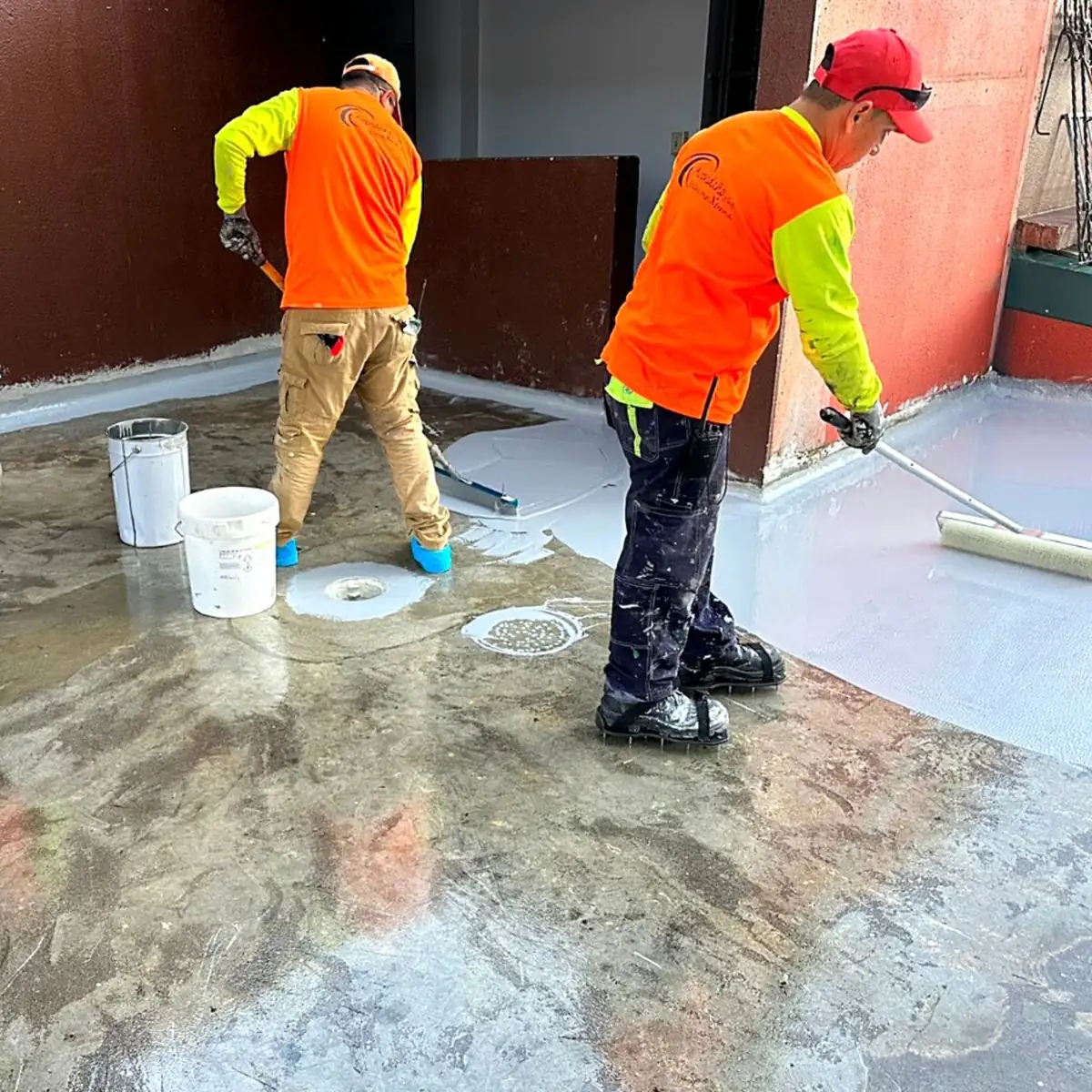 Workers rolling the coat near the red walls and white buckets Workers rolling the coat near the red walls and white buckets