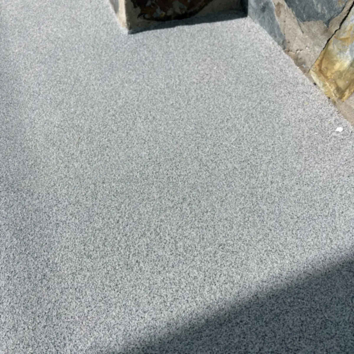 Encuentro del pavimento gris texturizado con un pilar revestido de piedra, Puerto Rico