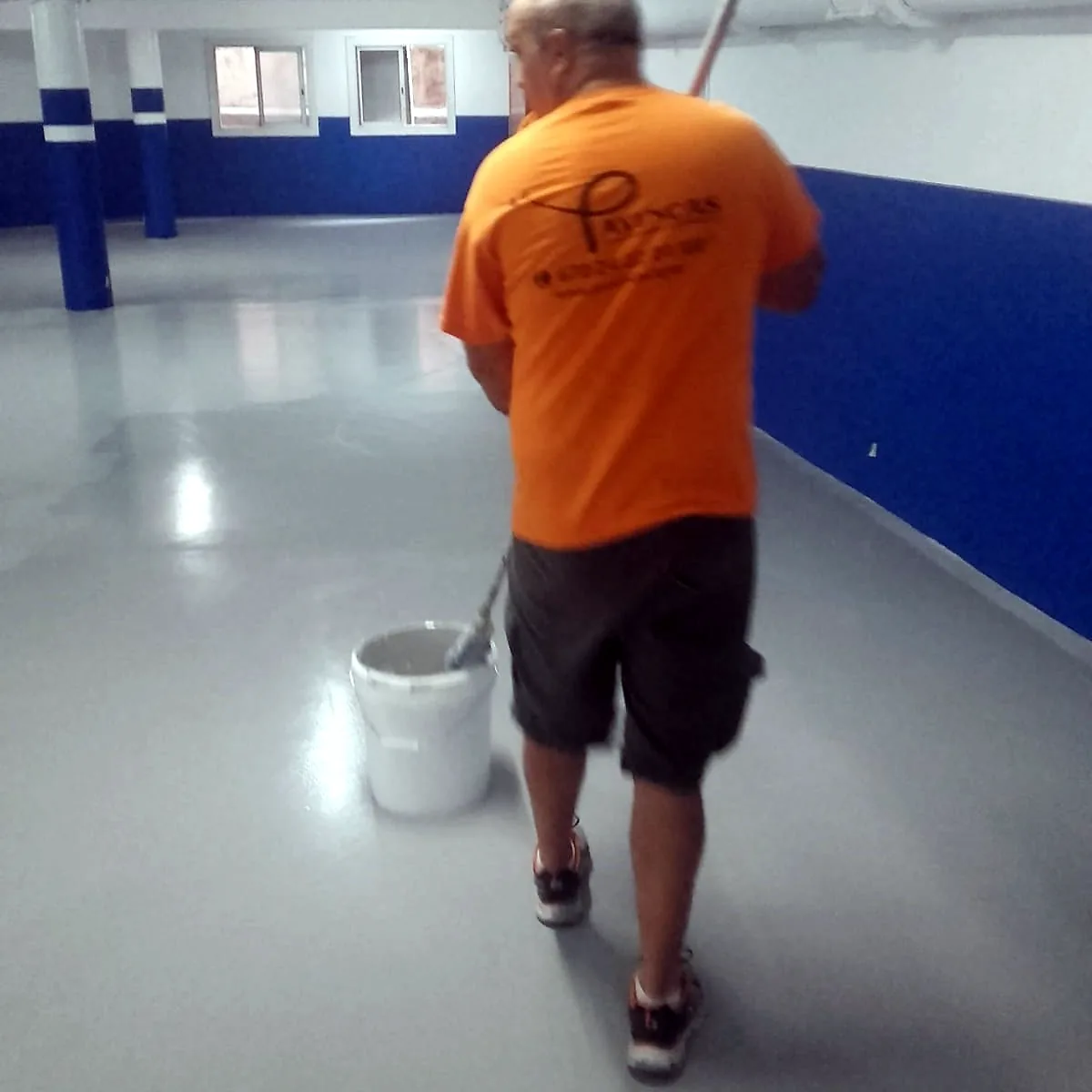 Applicator rolling the coat with a bucket at his side, hotel car park in Barcelona Applicator rolling the coat with a bucket at his side, hotel car park in Barcelona