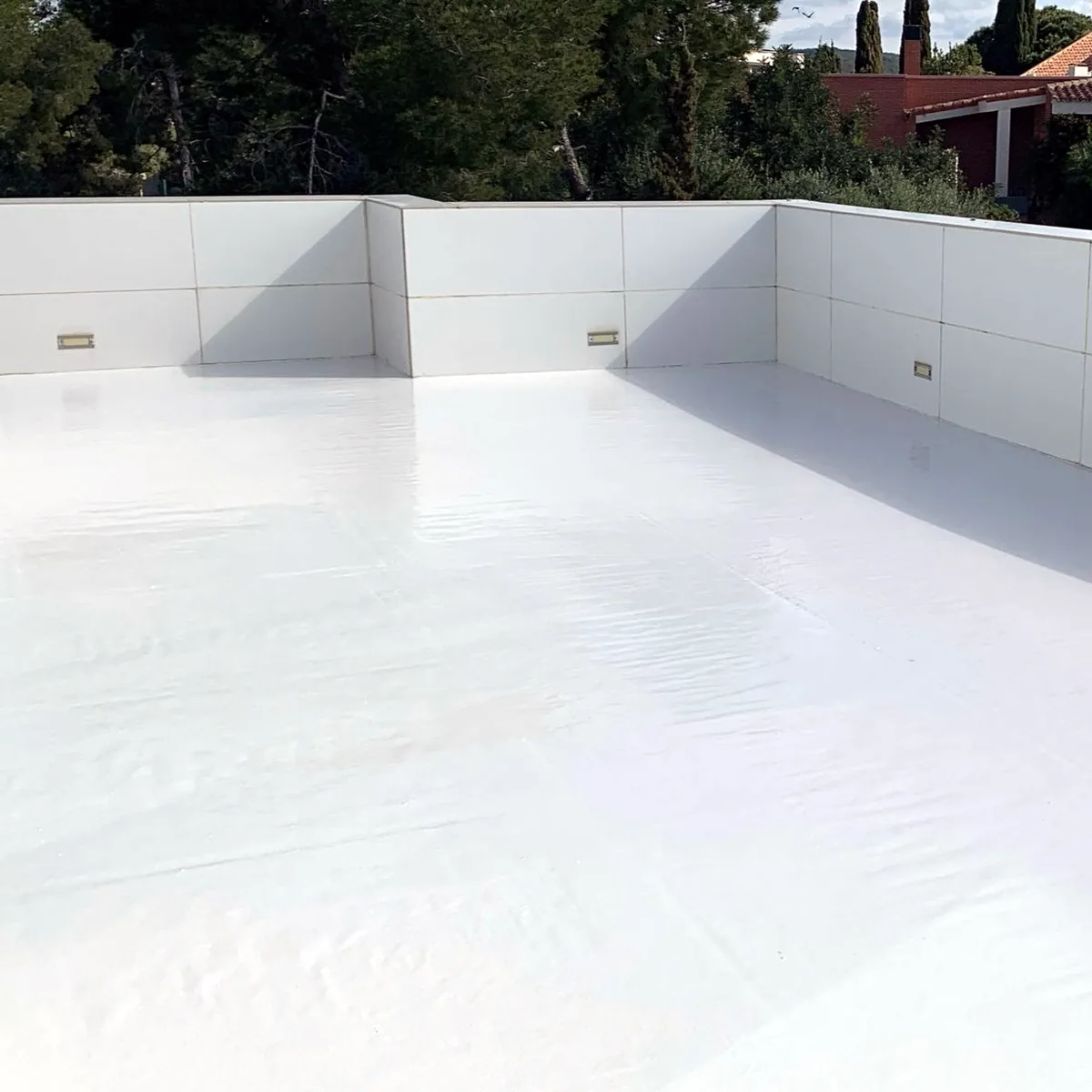 Smooth cool roof finish meeting the tiled parapet corner