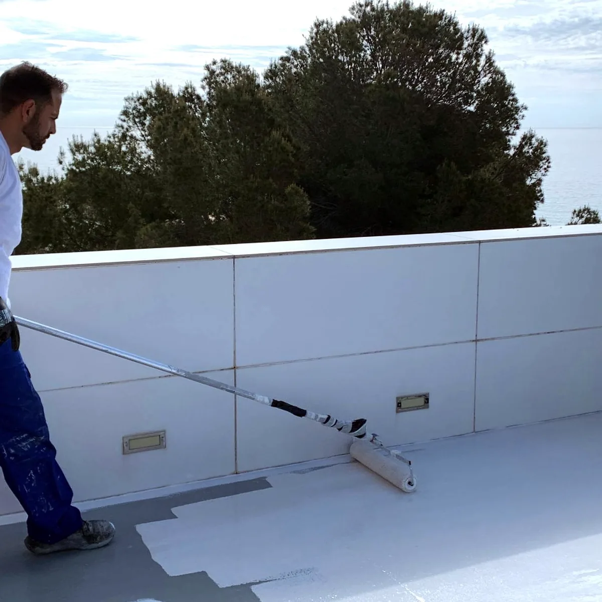 Applicator rolling the white Colodur topcoat over the membrane, Tarragona