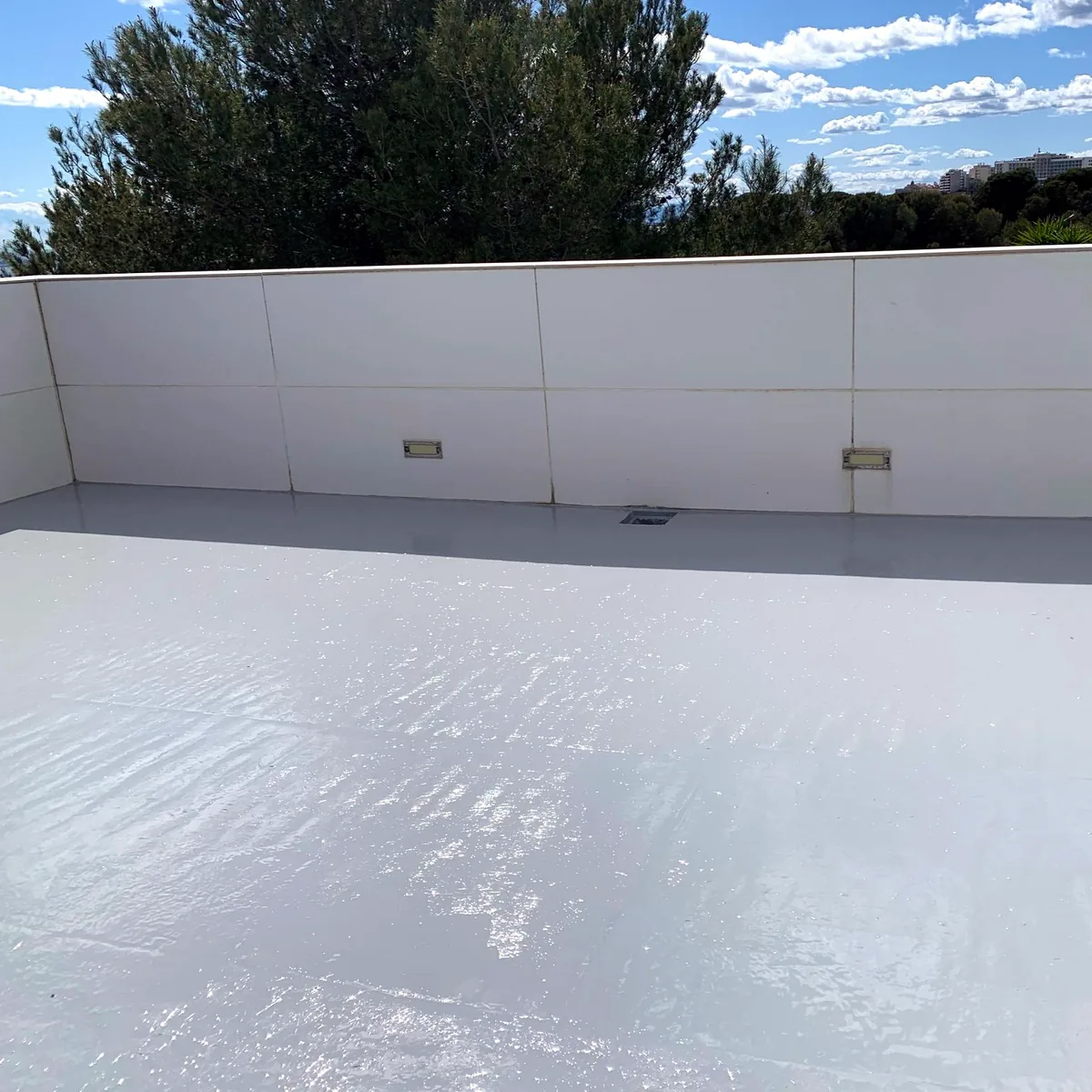 Light grey roof finish under a blue sky and pines, Platja Arrabassada