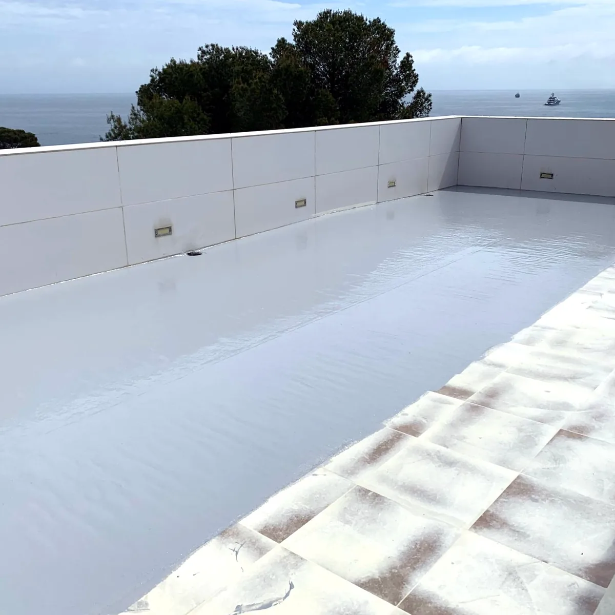 Light grey membrane running up to a strip of old roof tiles