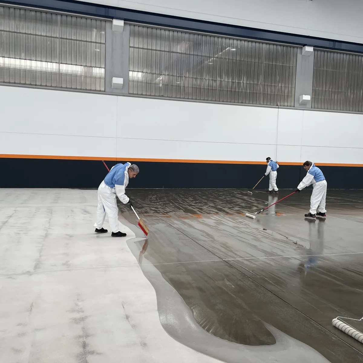Crew spreading grey epoxy across the open factory floor, Galicia Crew spreading grey epoxy across the open factory floor, Galicia