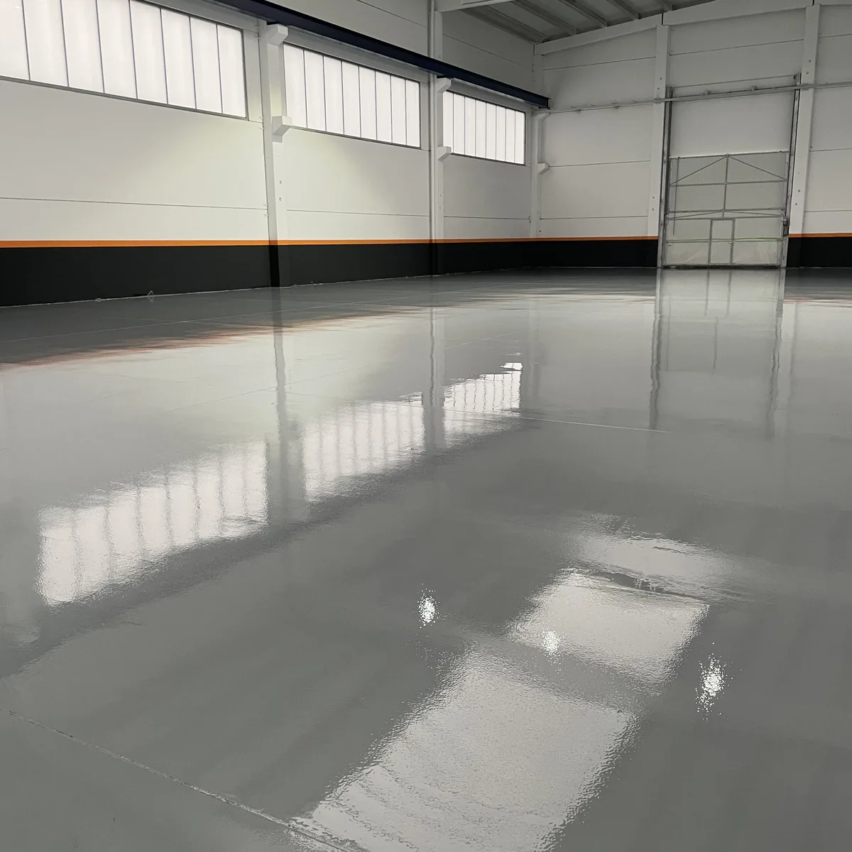 Finished factory bay floor in grey epoxy with roller doors, Galicia Finished factory bay floor in grey epoxy with roller doors, Galicia