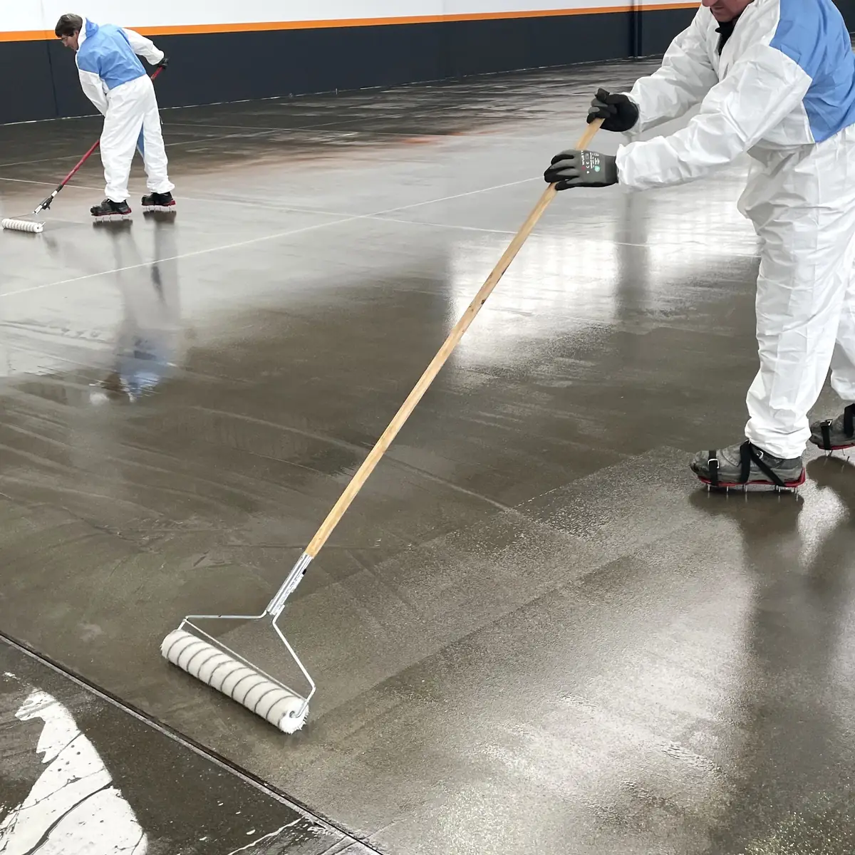 Applicator rolling epoxy primer onto the concrete slab, A Coruña factory Applicator rolling epoxy primer onto the concrete slab, A Coruña factory