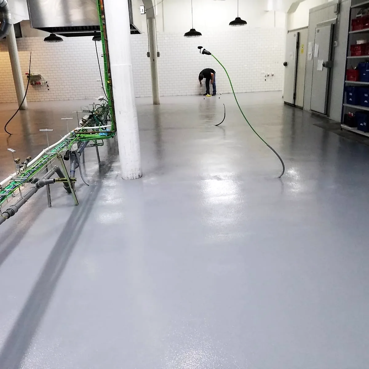 Kitchen floor during the works, with hoses and a worker in the background, Barcelona