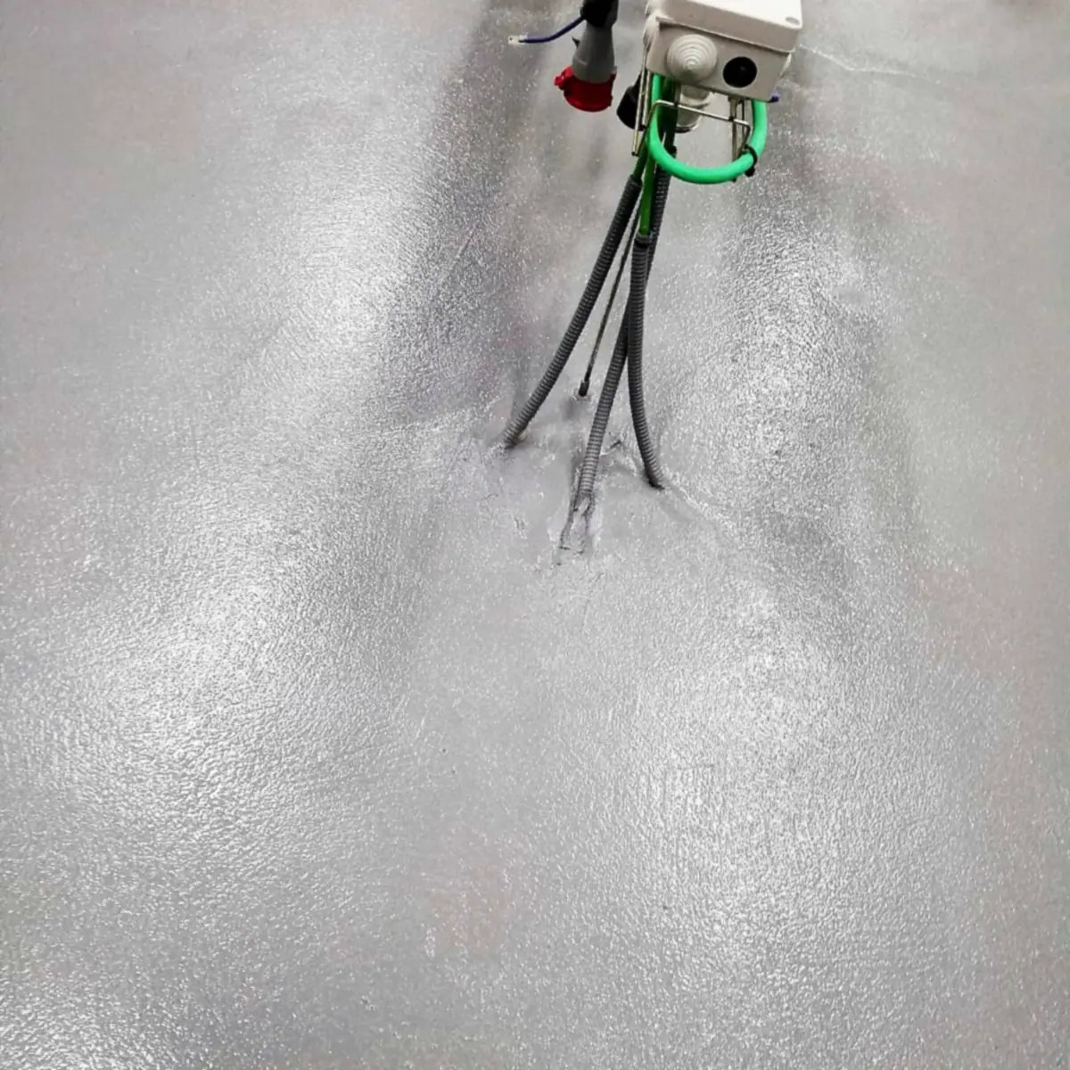 Grey epoxy floor around a service box with cables in the Barcelona kitchen