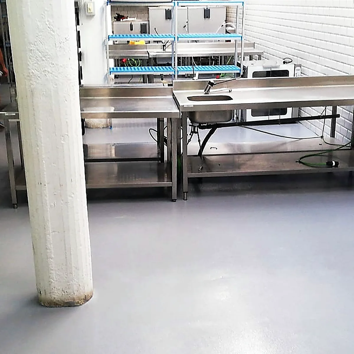 Stainless prep tables and white columns on the grey epoxy floor, Barcelona kitchen