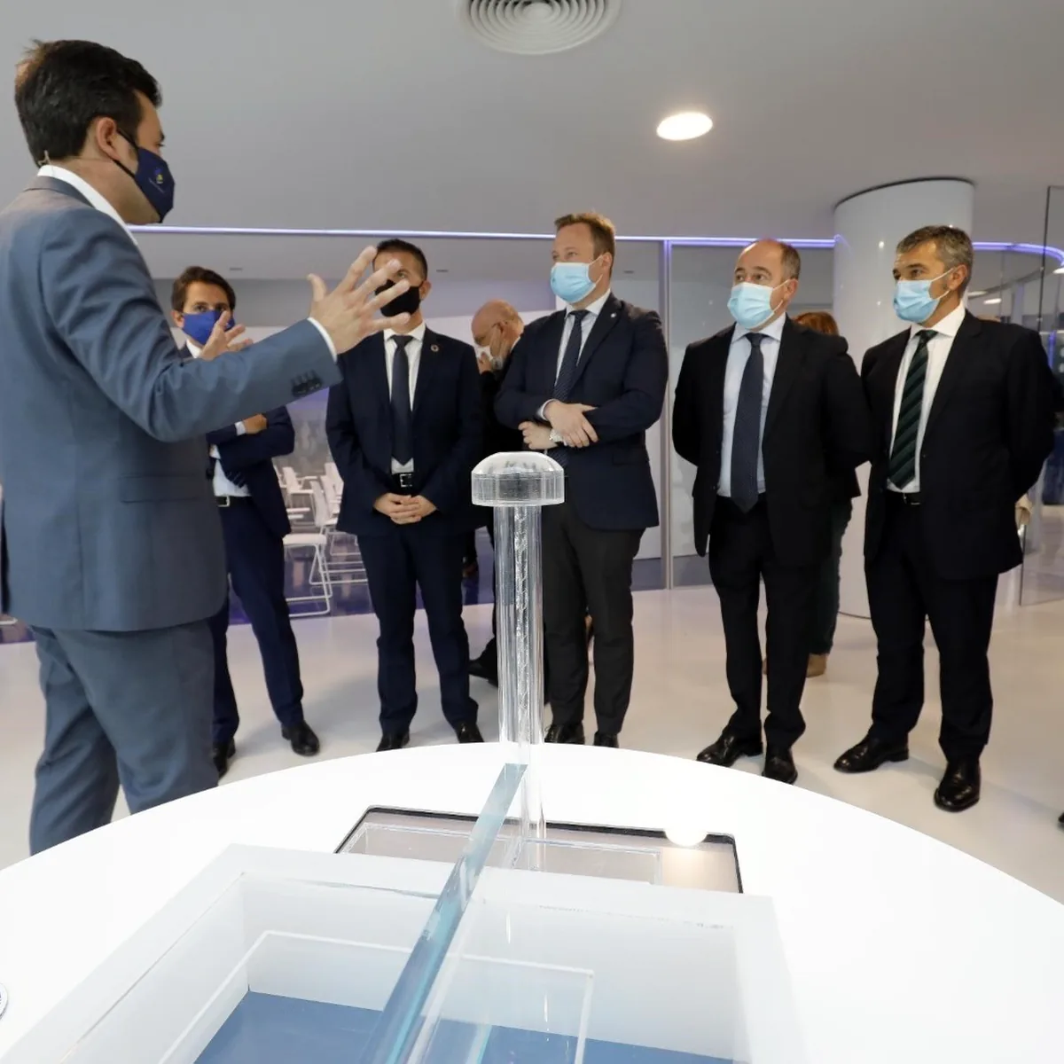 Visitors standing on the white resin floor beside a display table, Albacete
