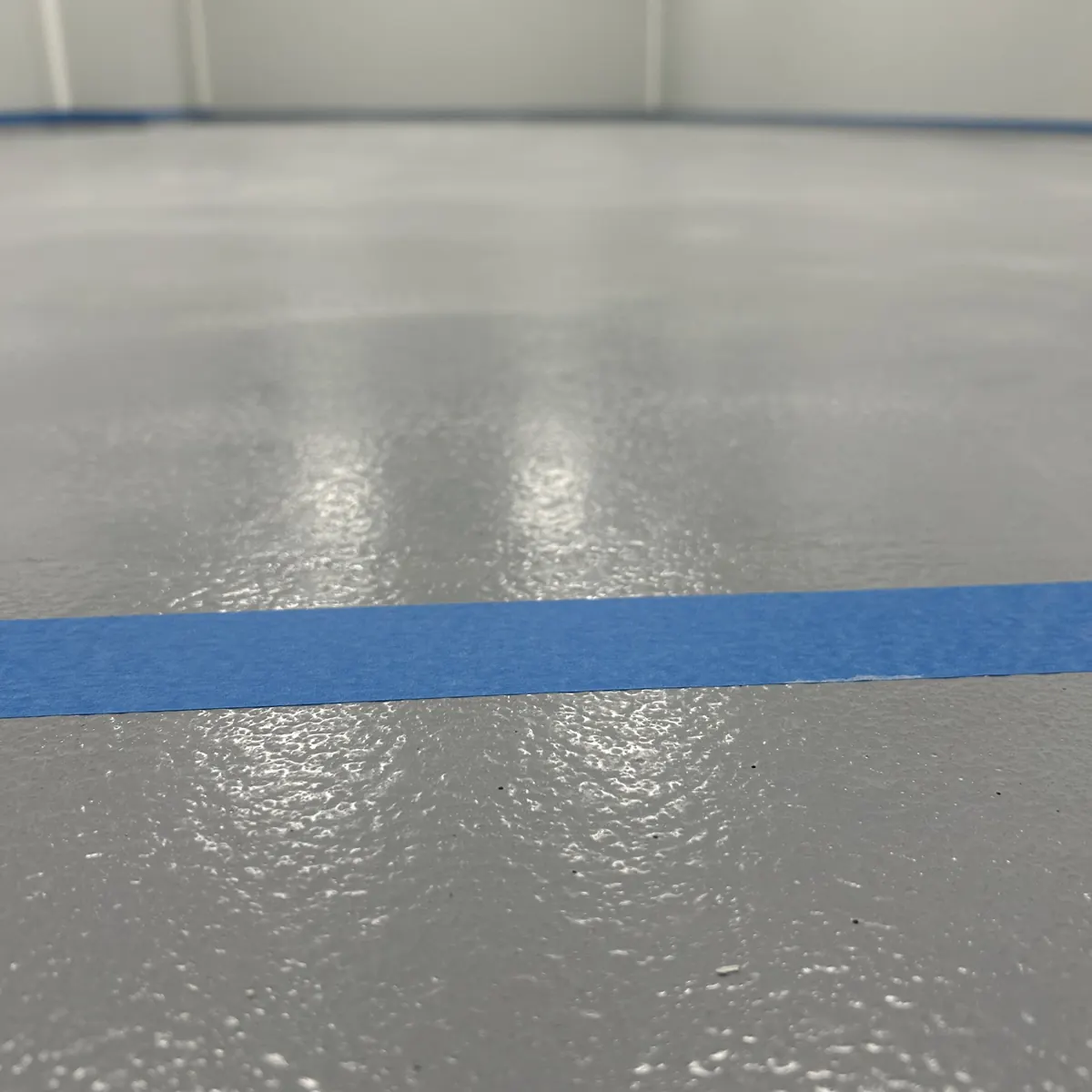 Detalle de la textura del pavimento epoxi gris con cinta de enmascarar azul, Aiguaviva