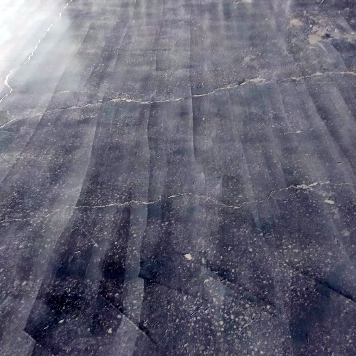 Grey slab with filled cracks visible under a glossy film, Porto factory