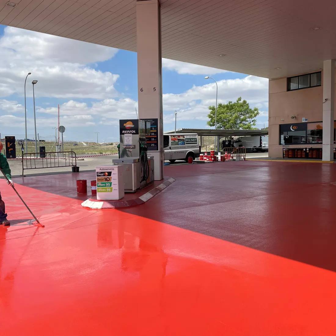 A worker with a roller on the red forecourt A worker with a roller on the red forecourt