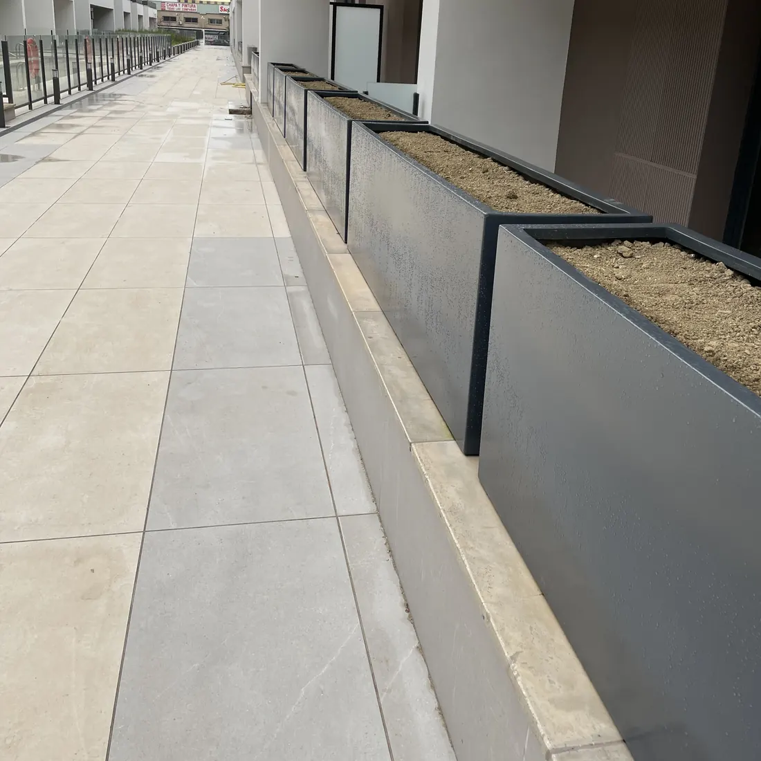 Tramo de jardineras junto a un paseo de pavimento claro Tramo de jardineras junto a un paseo de pavimento claro