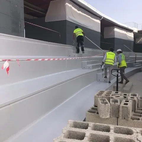 A worker rolling the light grey coat on the concrete steps A worker rolling the light grey coat on the concrete steps