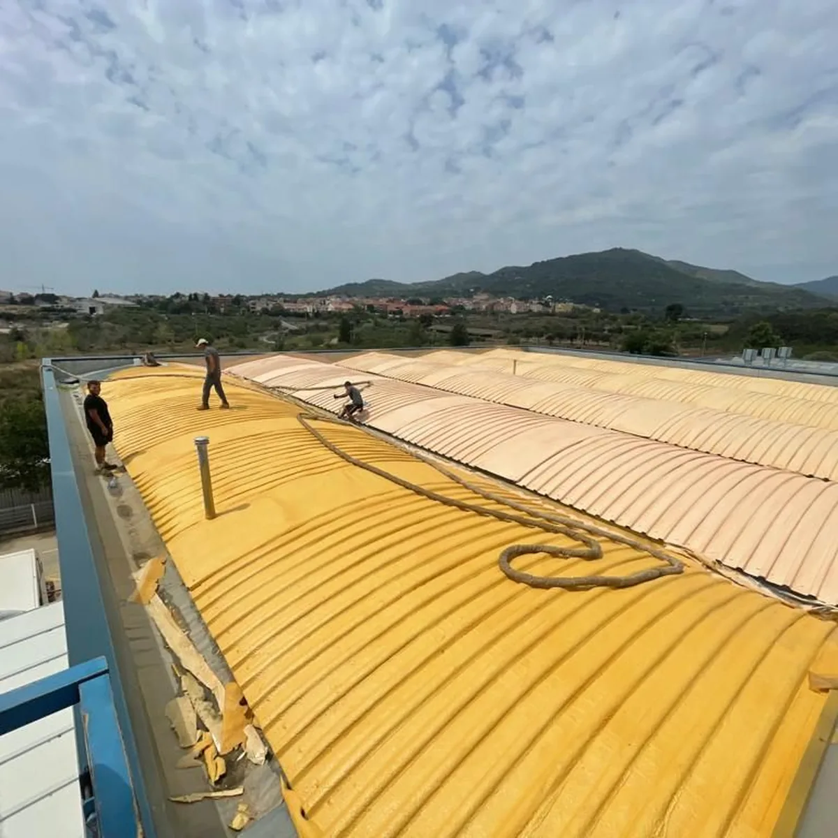 Yellow spray foam over the metal sheet roof of an industrial building, Tarragona