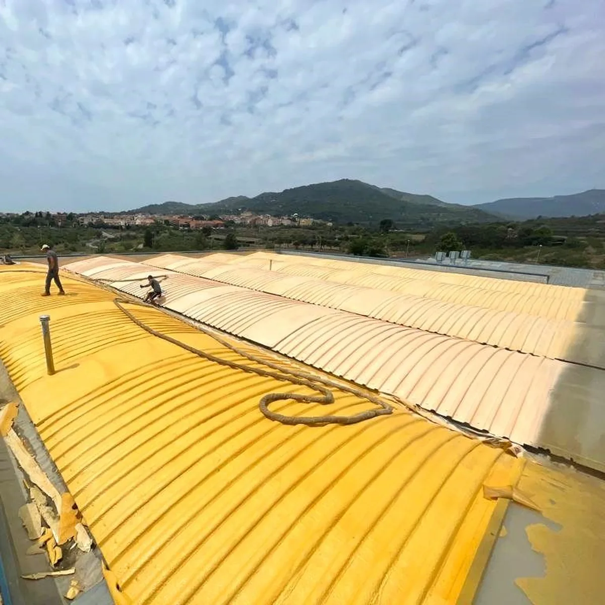 Spray hoses across the foamed ribs on the warehouse roof, Tarragona