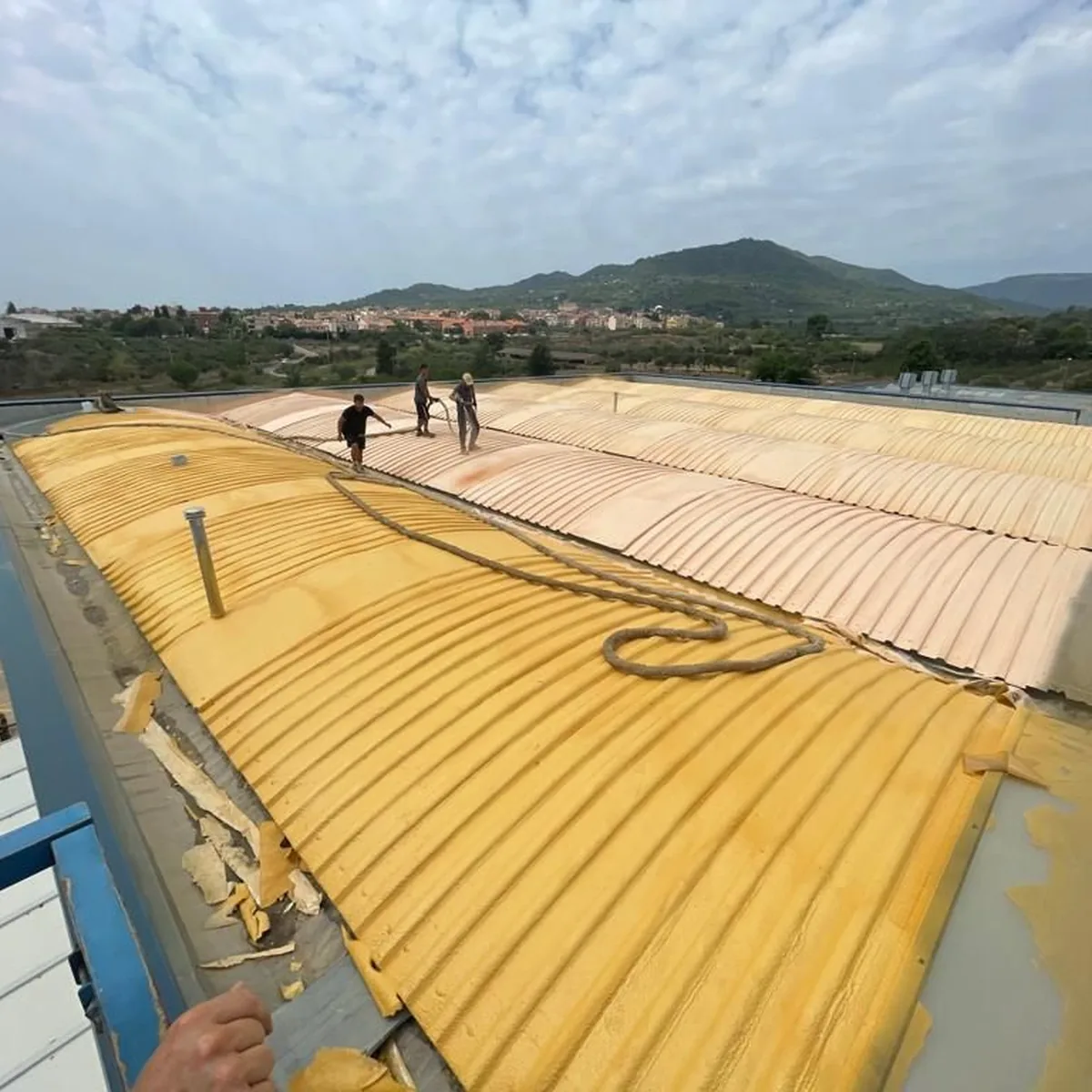 Crew walking the foamed ribs of the warehouse roof, La Selva del Camp